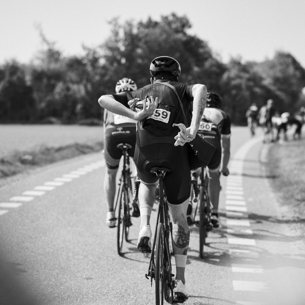 Cyclists racing on road in black and white, showing teamwork and competition during cycling event