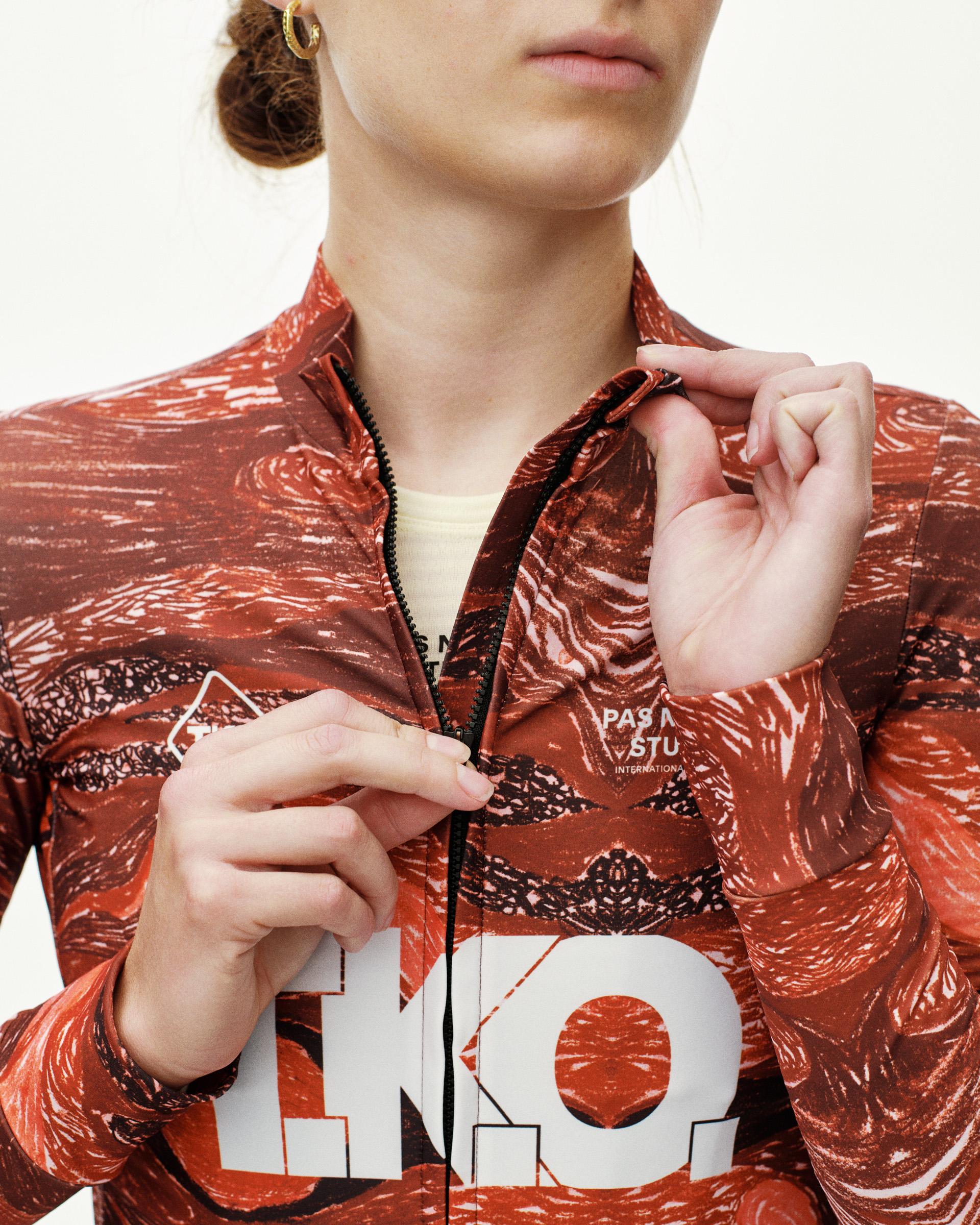 Red T.K.O. Mechanism women's long sleeve cycling jersey, front detail on model with allover print and white T.K.O. chest logo