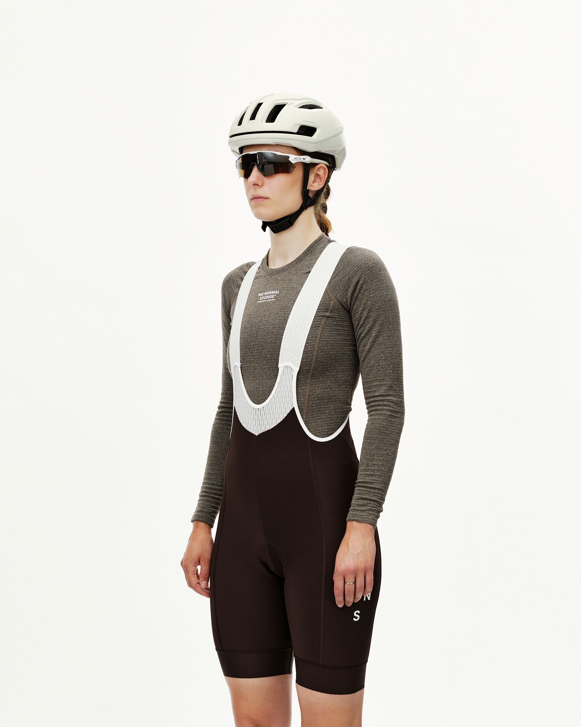 Dark Coffee brown Mechanism Thermal women's cycling bibs on model, front view with white ribbed bib straps