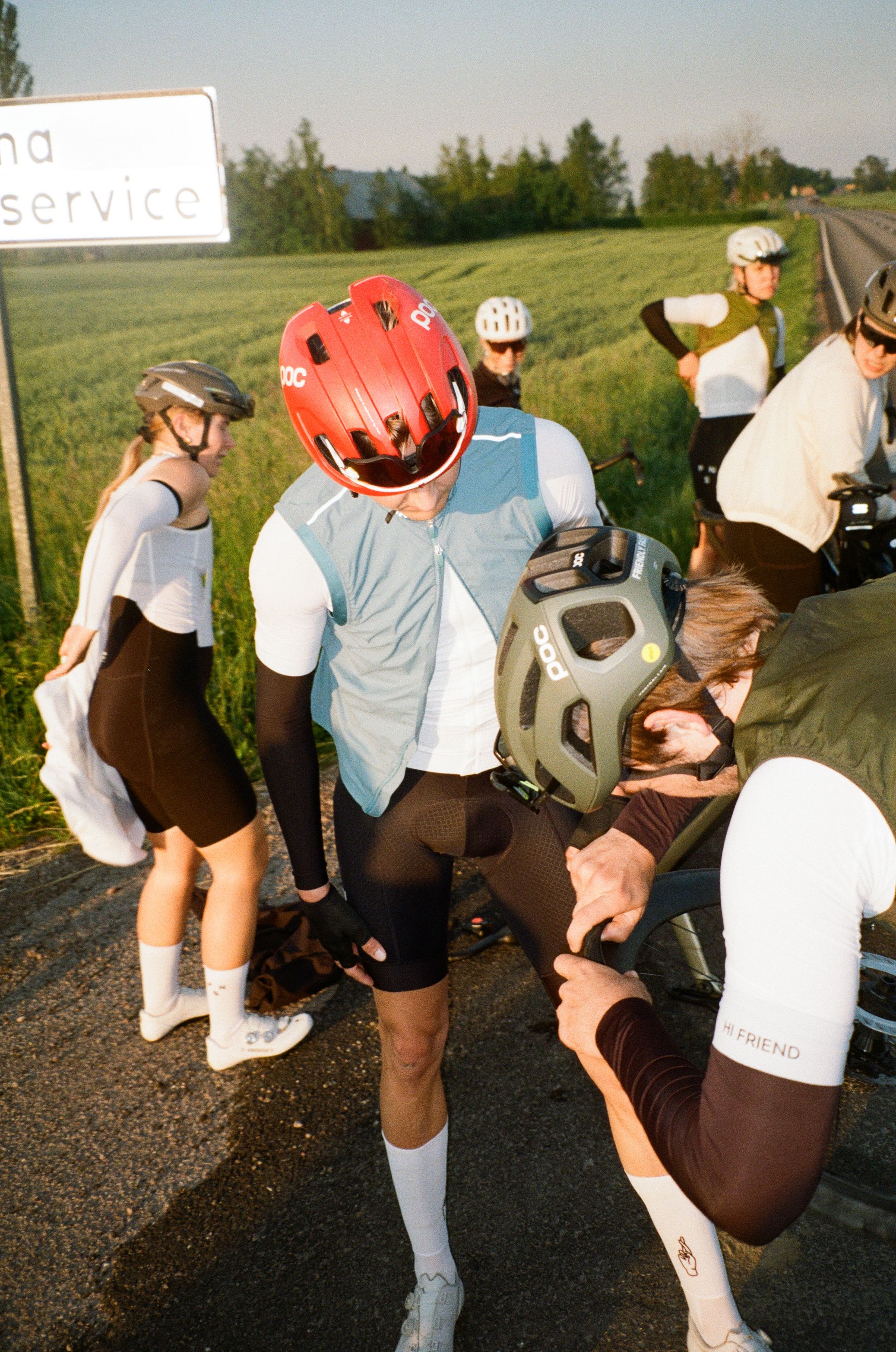 Cyclists in white jerseys and time trial helmets preparing on roadside during race