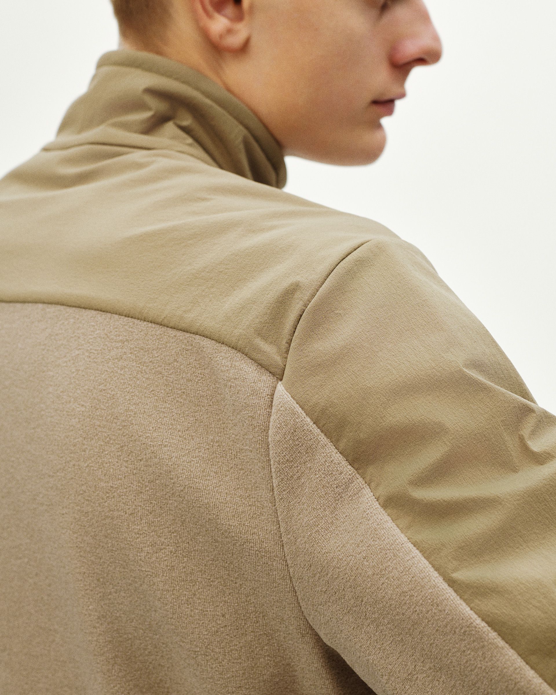 Beige Off-Race Light Fleece half-zip on model, rear three-quarter view showing contrast panel construction