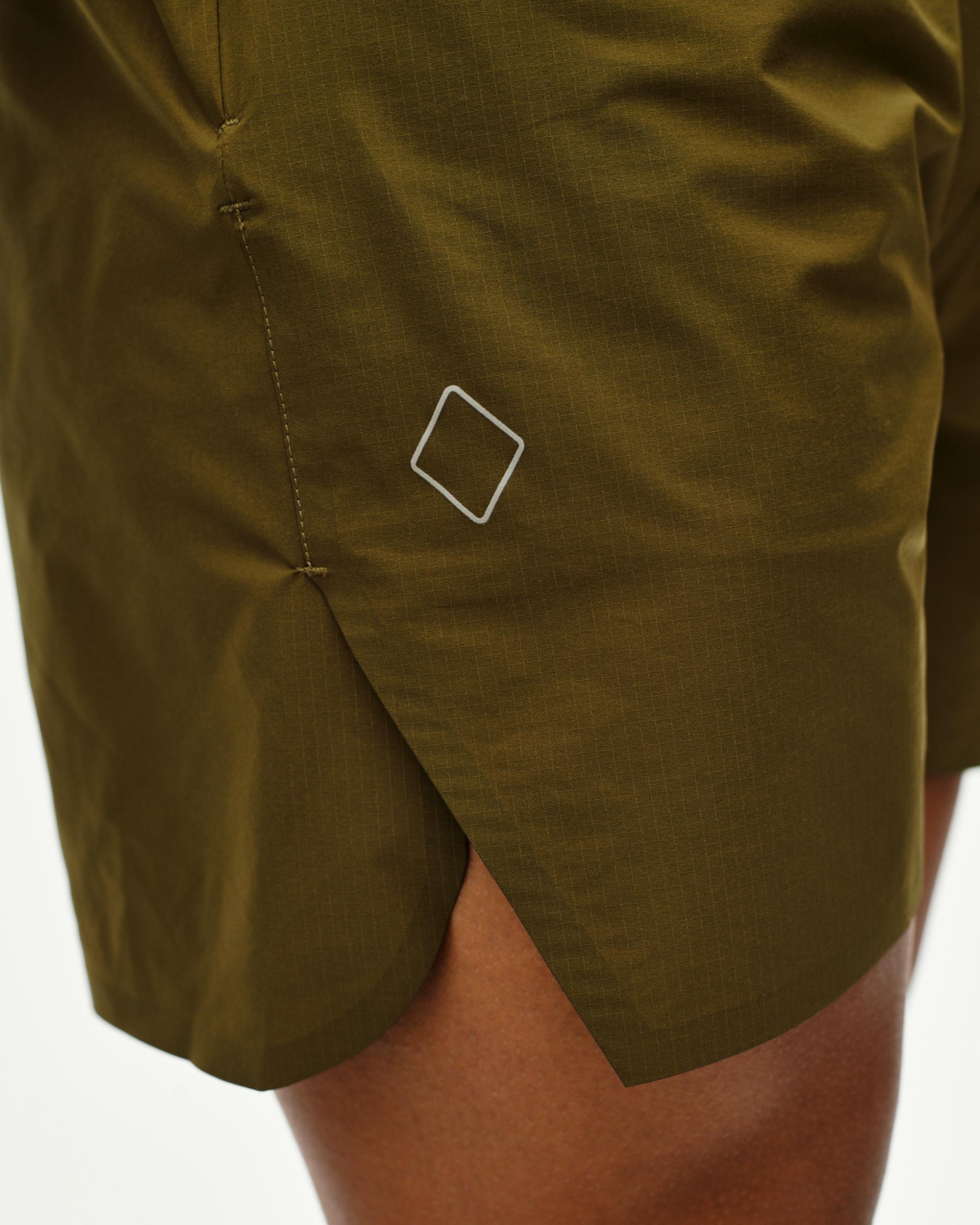 Moss Brown Balance shorts, side detail on model with diamond logo and side vent