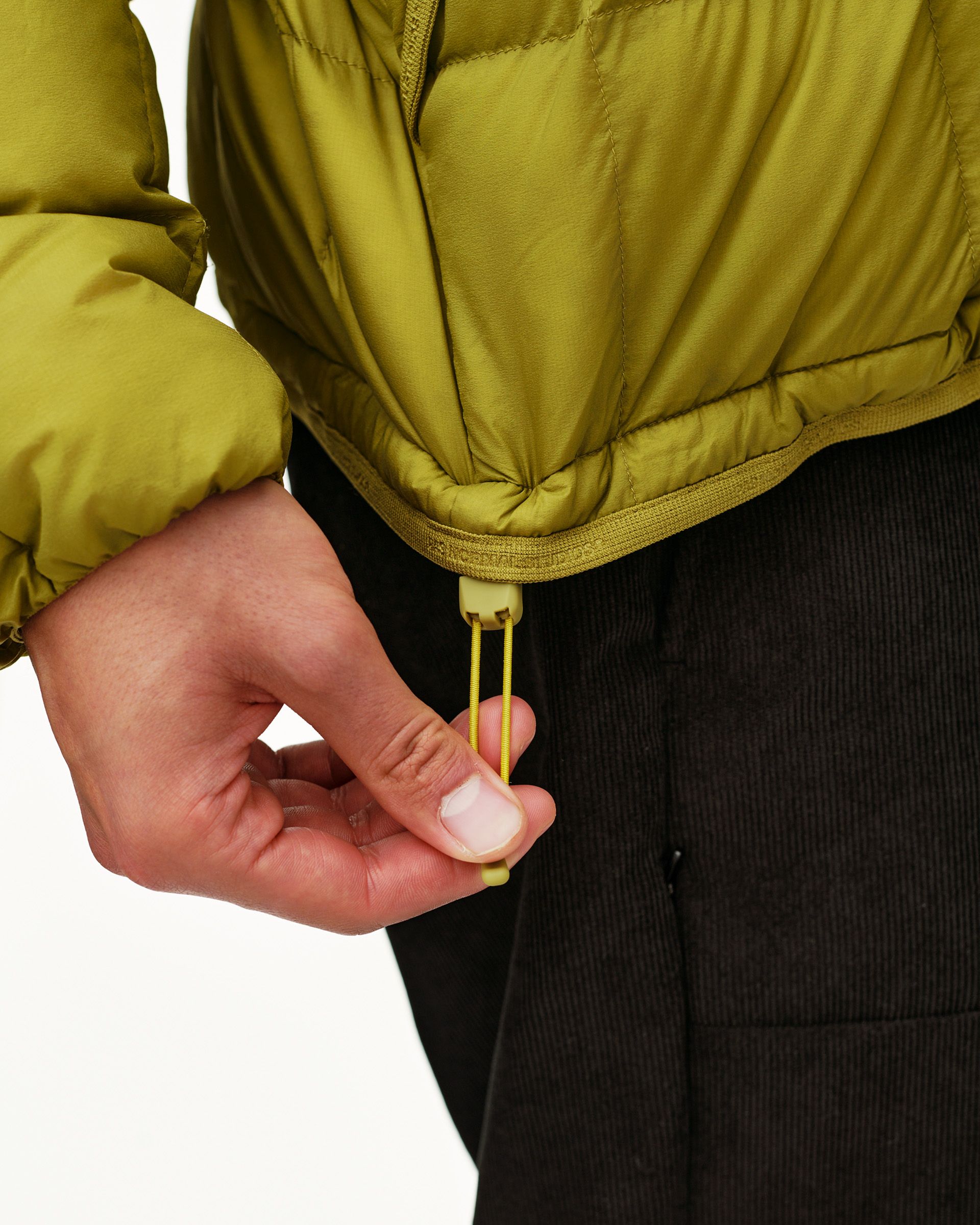 Dark Lime green Off-Race Down Liner jacket, detail on model showing hem drawcord toggle