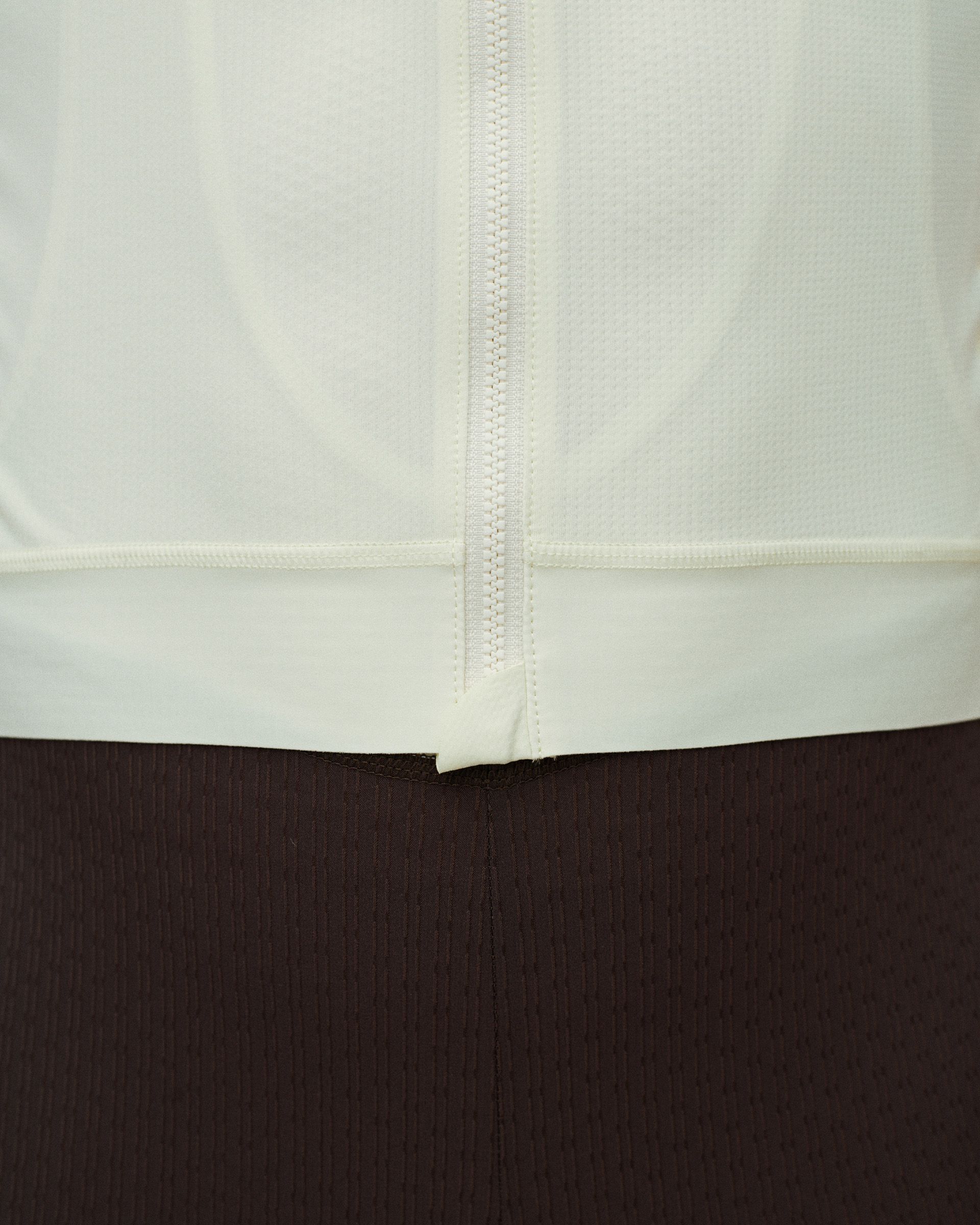 Off White Essential cycling jersey, front detail view showing full-length zip and textured fabric hem