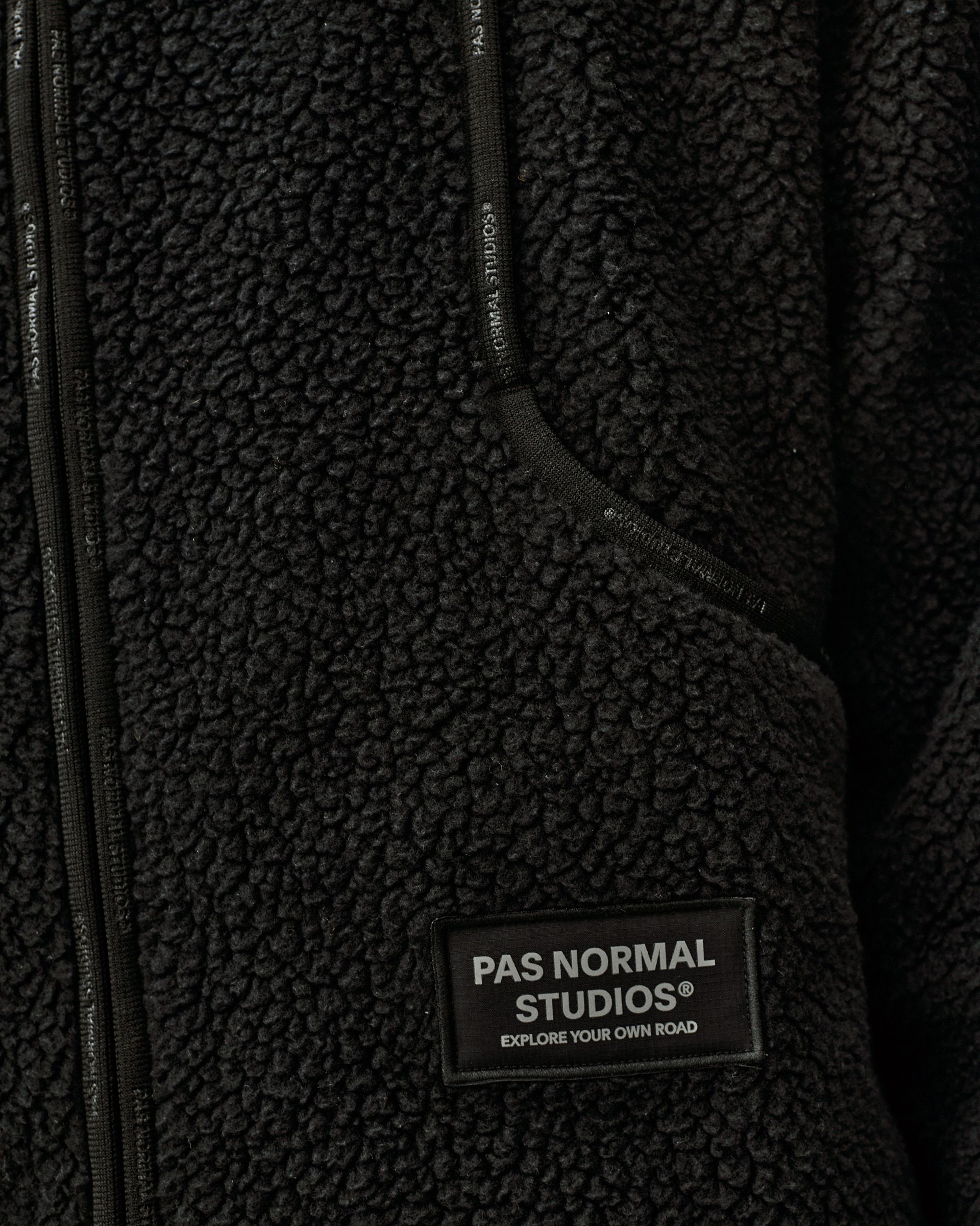 Black Off-Race Pile Fleece jacket, detail view of chest pocket and zip with woven brand label