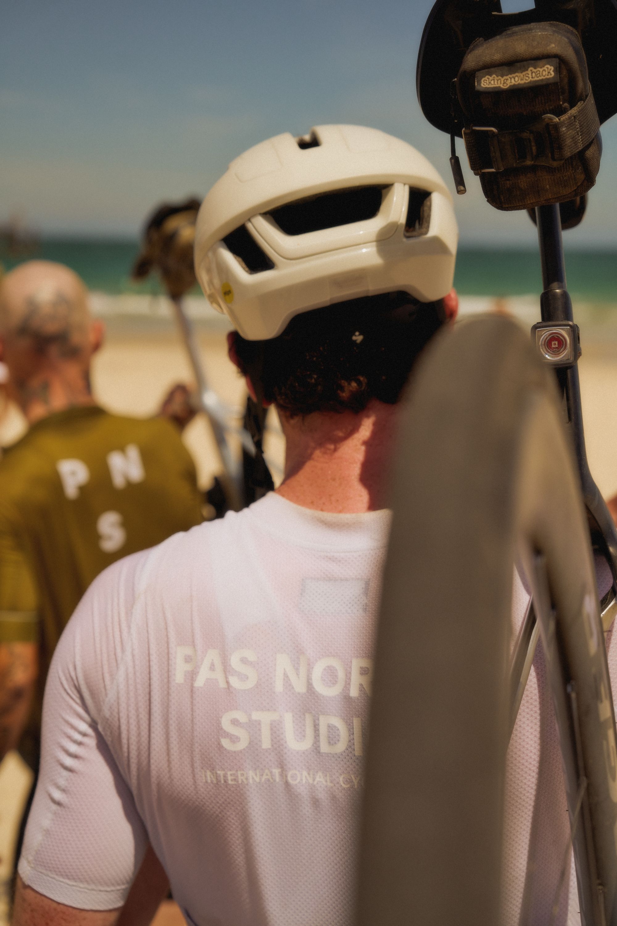 Model wearing white helmet and pink jersey with text branding at beach setting