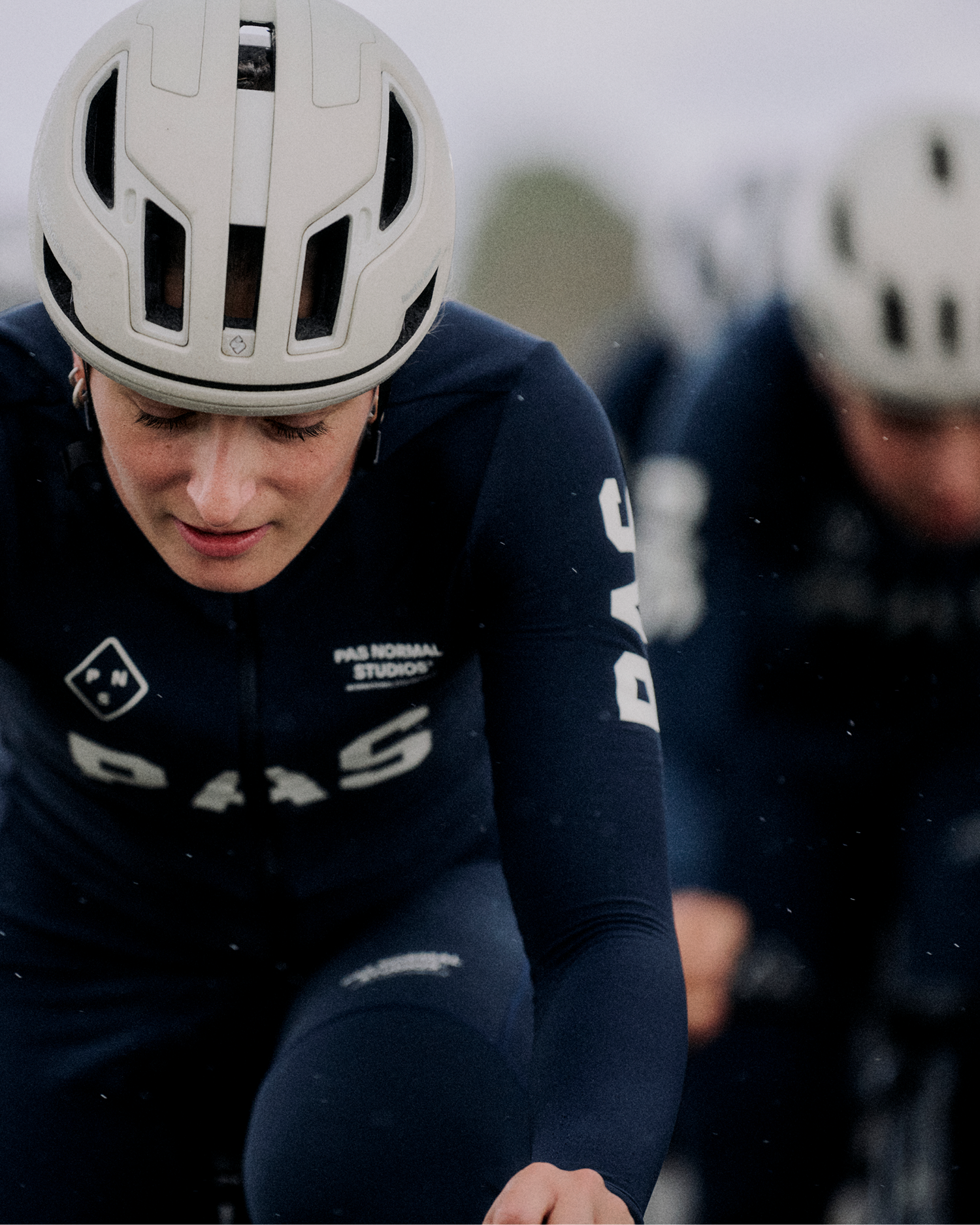 Model wearing navy PAS collection cycling kit with white helmet during outdoor training