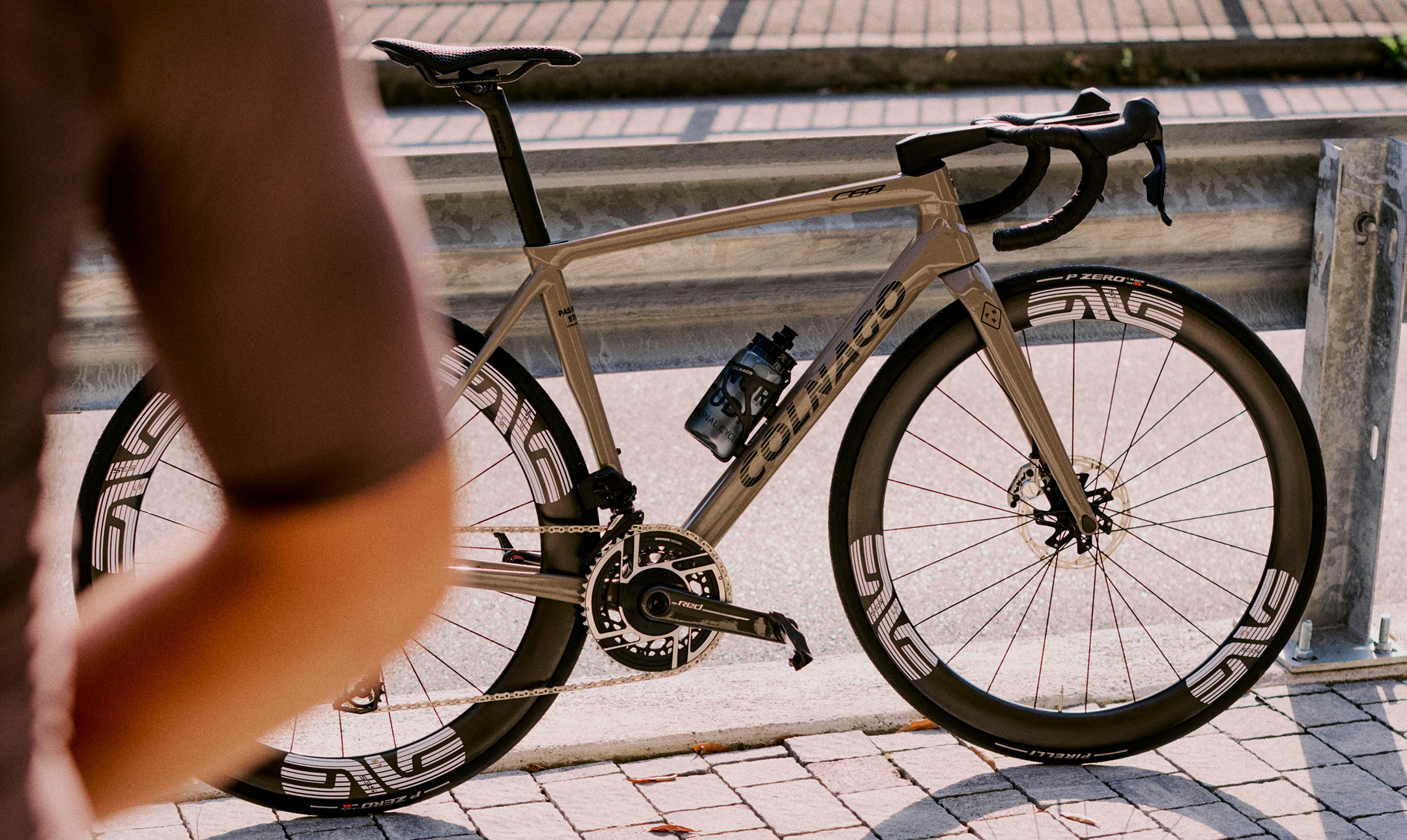 High-performance road bike with aerodynamic tan frame and deep carbon wheels on cobblestone street