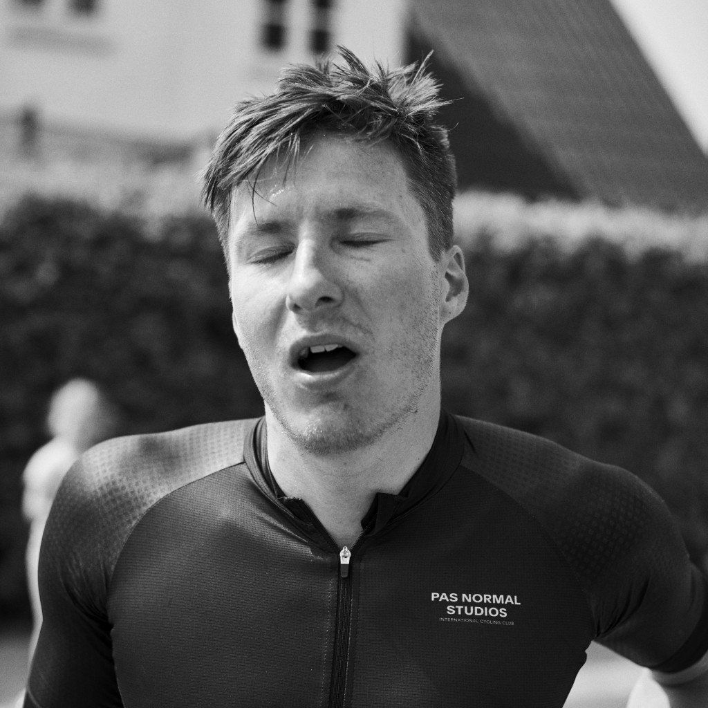 Cyclist wearing dark cycling jersey with logo during intense effort, black and white photo
