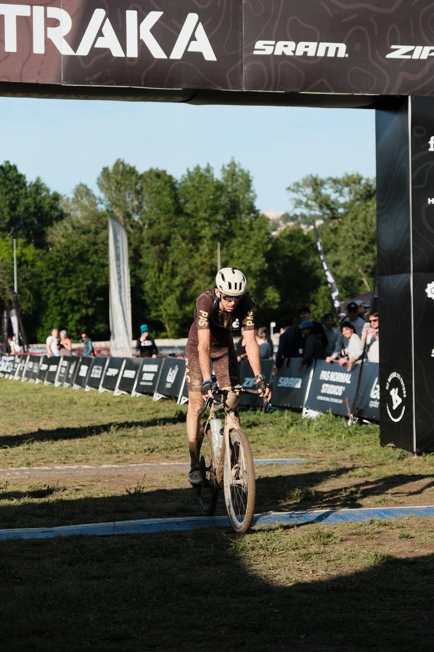 Cyclist in black kit racing through finish line at Traka gravel event