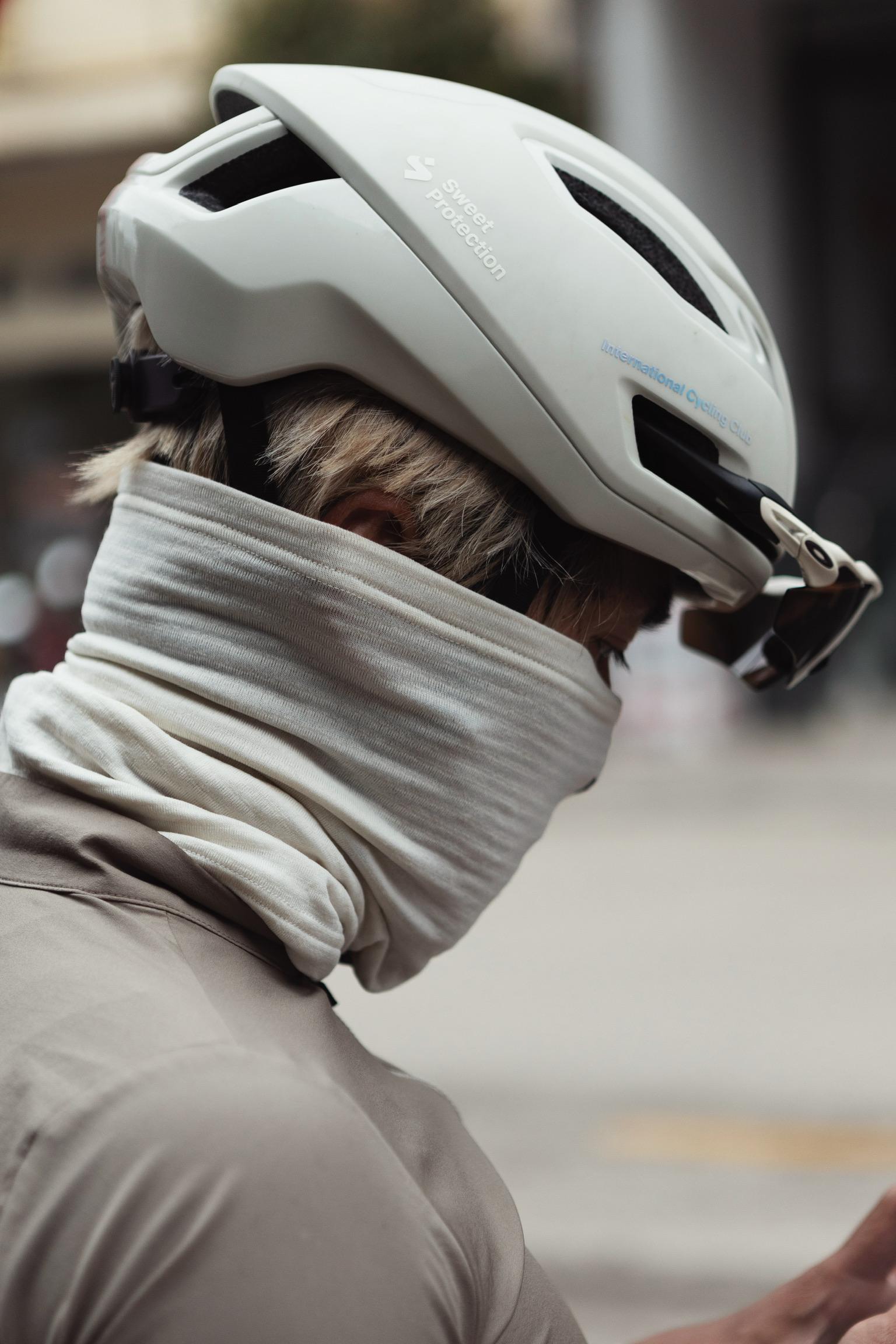 Model wearing white cycling helmet with grey striped neck warmer