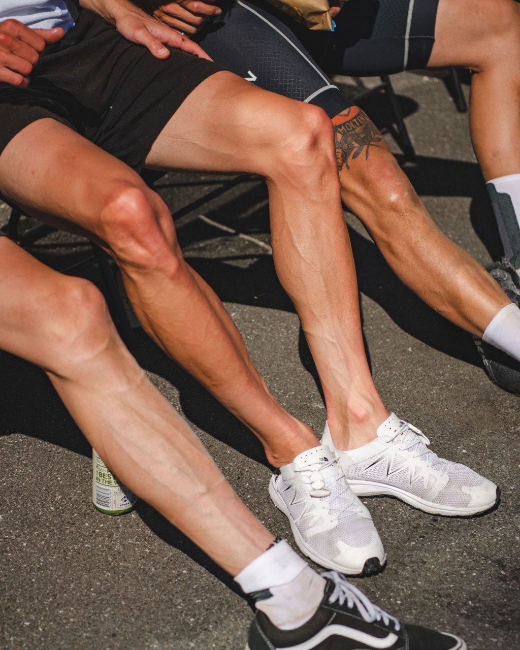 Cyclists resting with legs visible wearing white athletic shoes and socks