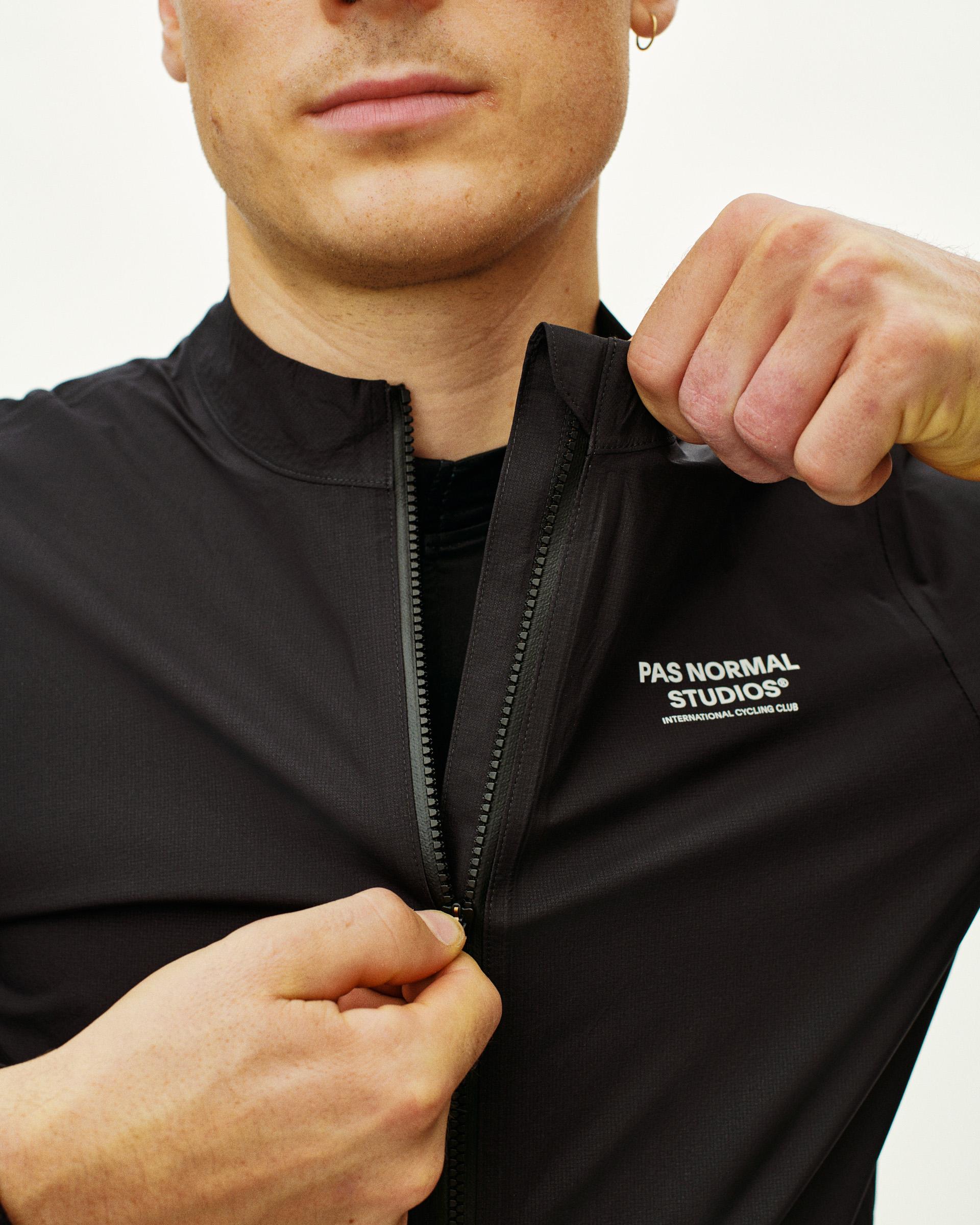 Black Mechanism Pertex Rain cycling jacket on model showing half zip and white chest logo