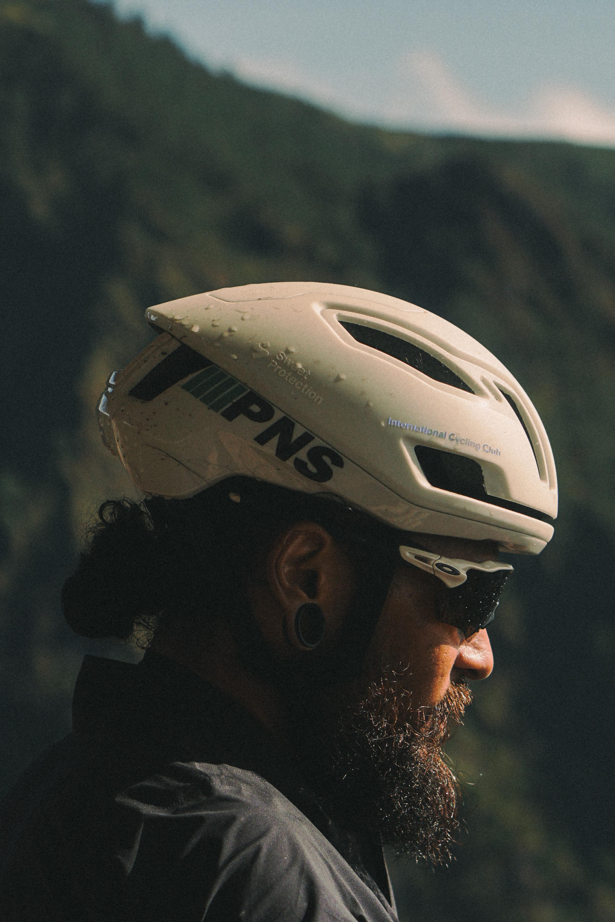 Model wearing white cycling helmet with branding outdoors in mountainous landscape