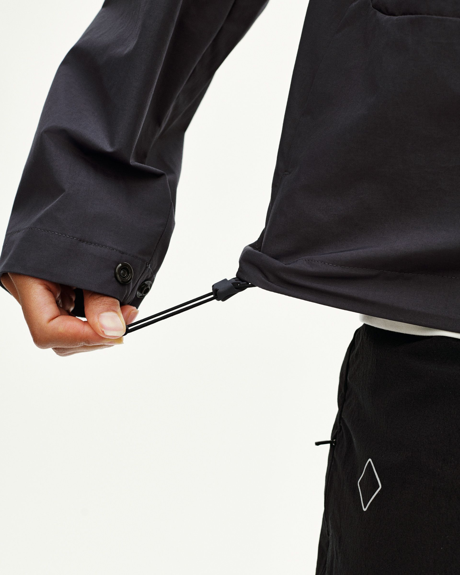 Black Off-Race Utility jacket detail showing adjustable hem drawstring with cord lock