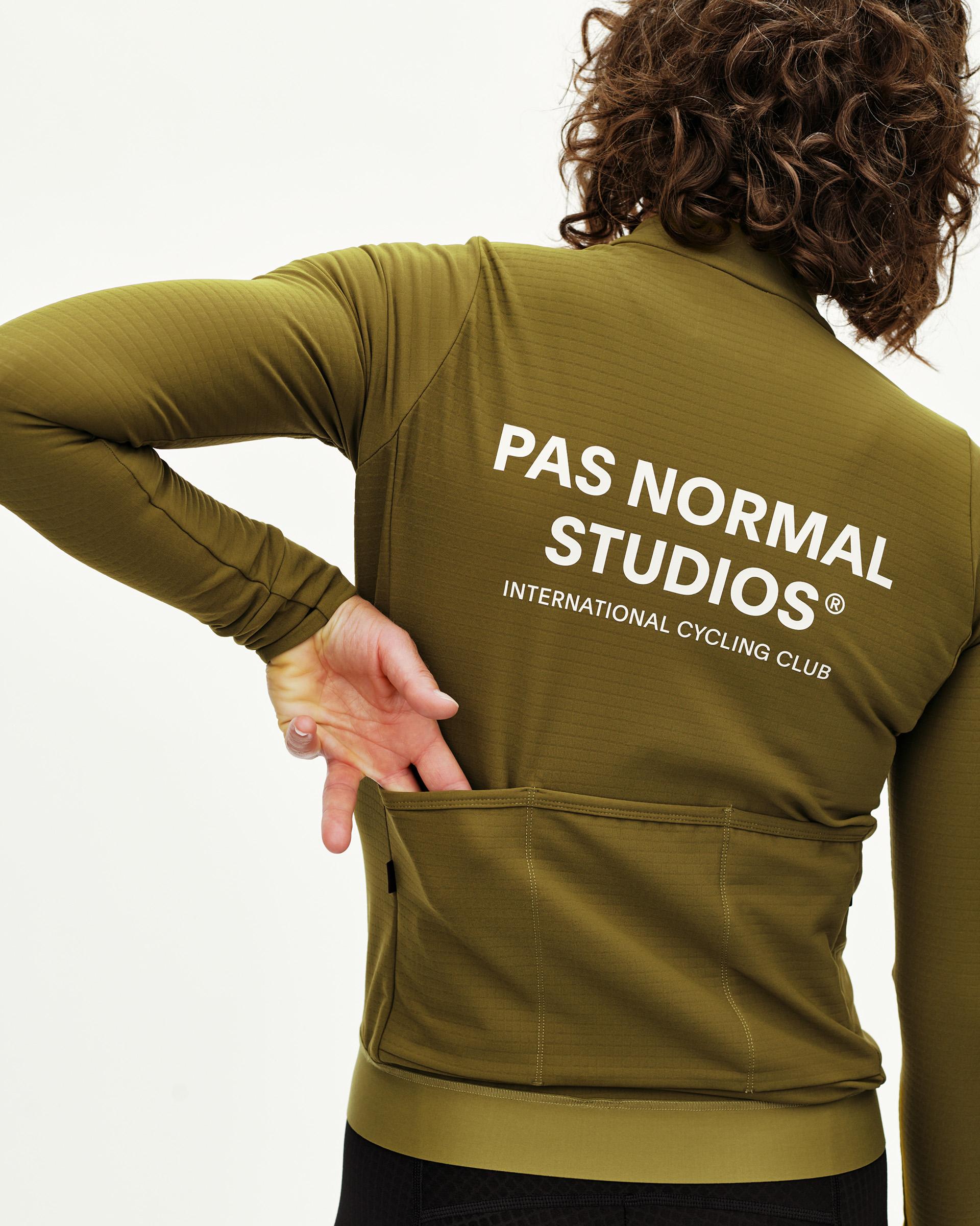 Khaki Green Essential long sleeve cycling jersey on model, rear view with white back print and pocket