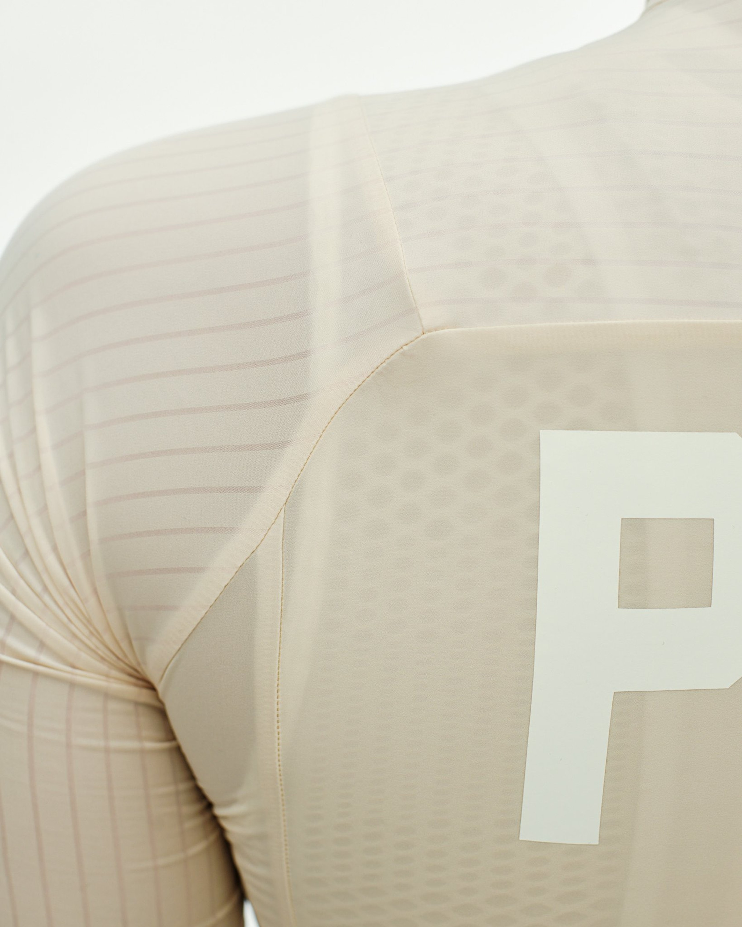 Beige PAS Mechanism Pro cycling jersey, side detail view with ribbed sleeve construction