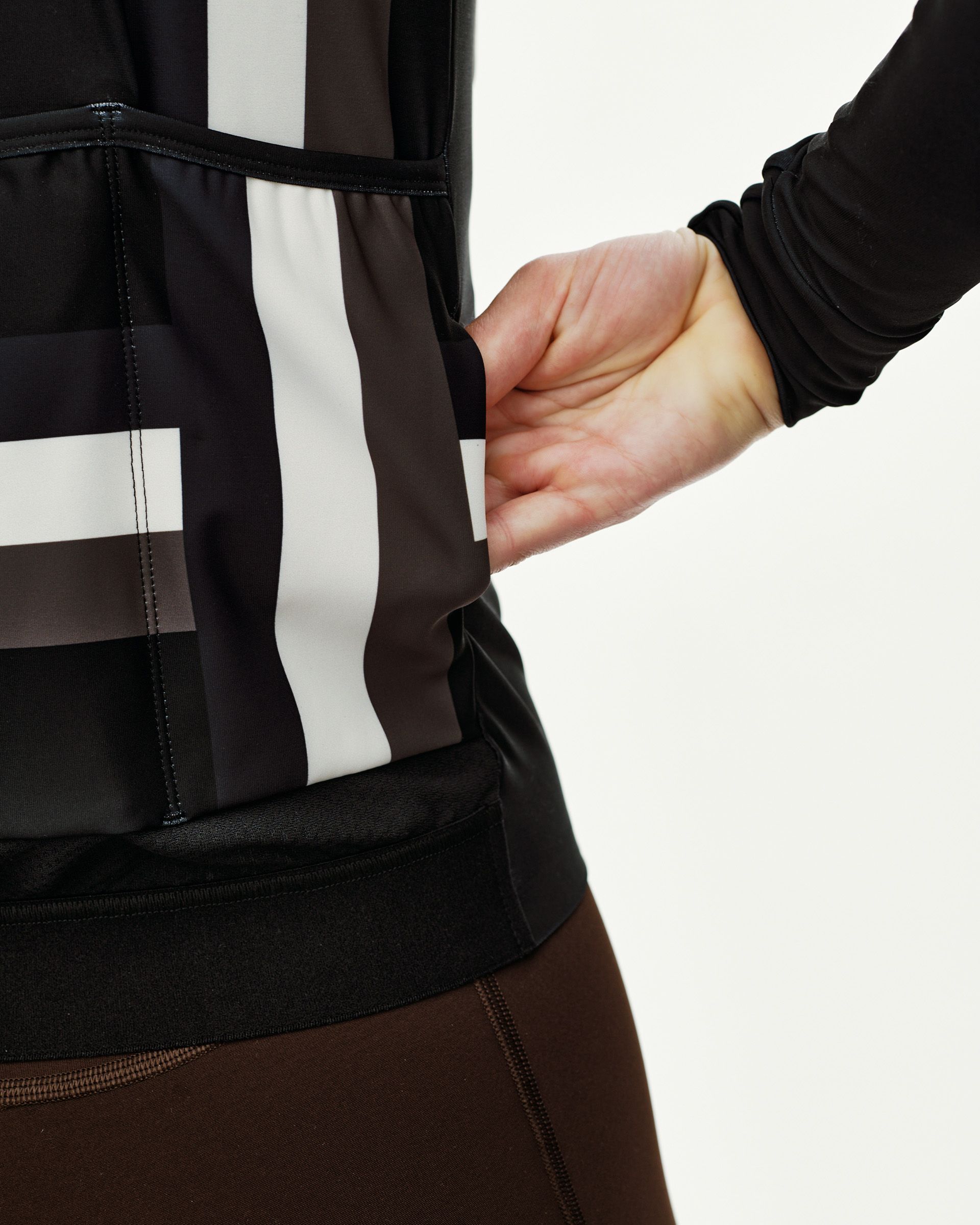 International Dark Olive Mechanism women's long sleeve cycling jersey, side view on model showing rear pocket and stripe