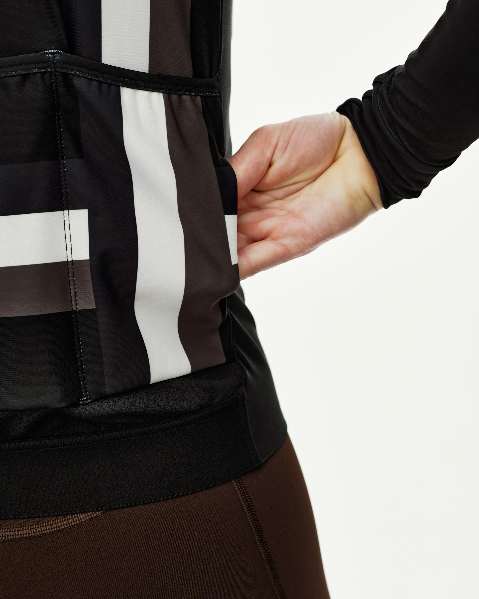 International Dark Olive Mechanism women's long sleeve cycling jersey, side view on model showing rear pocket and stripe