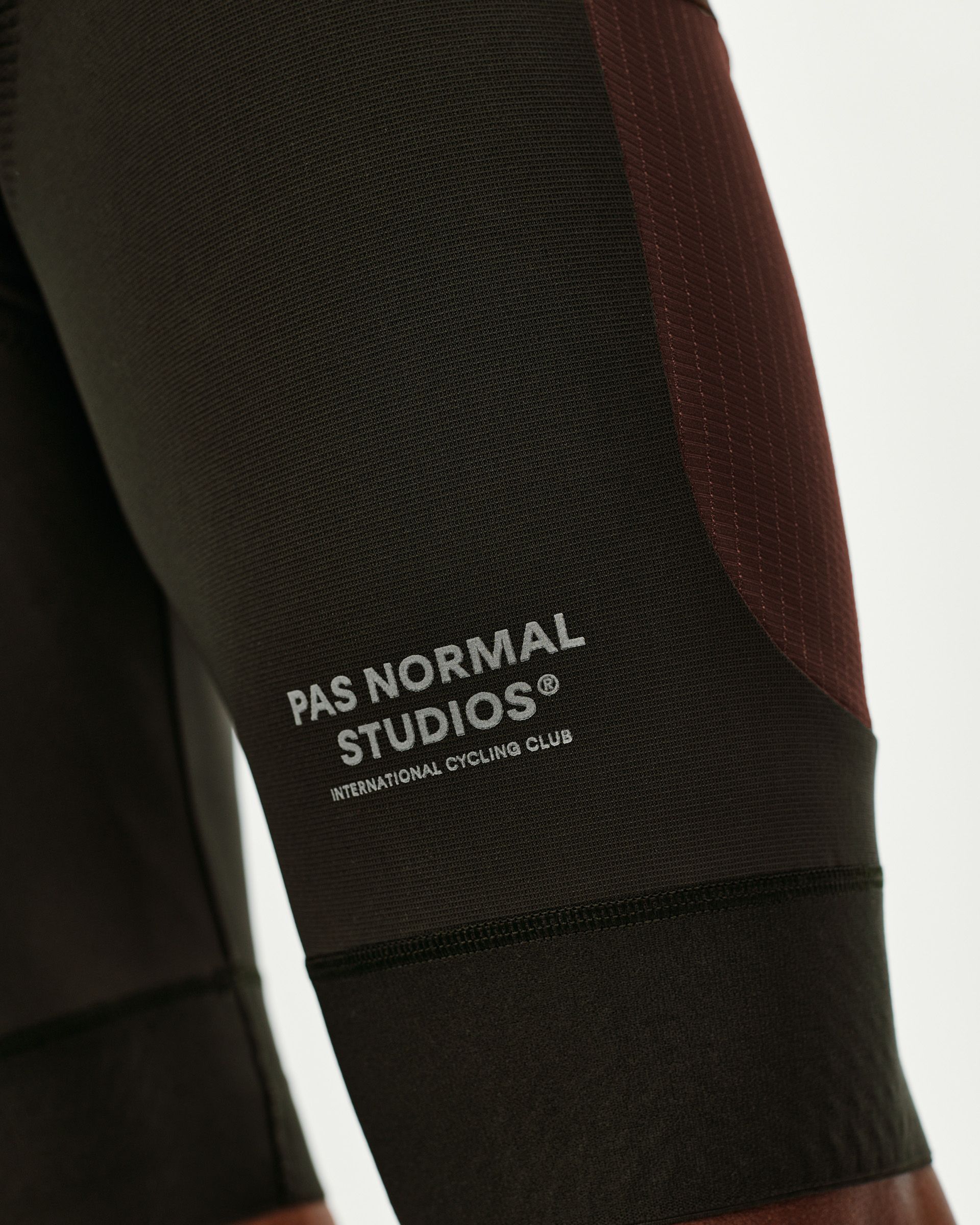 Dark Olive Escapism Cargo cycling bibs, side detail view with burgundy contrast panel and logo print