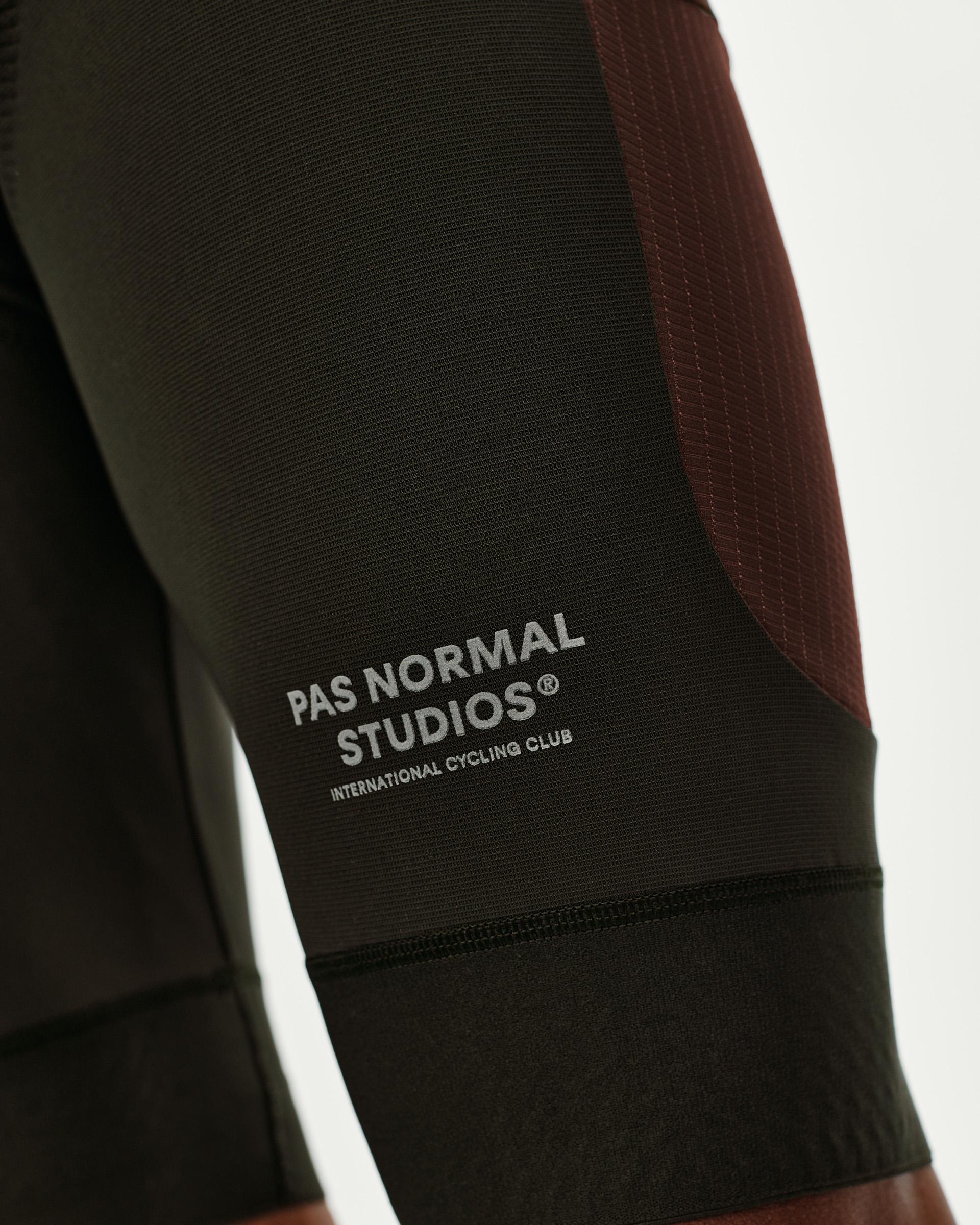 Dark Olive Escapism Cargo cycling bibs, side detail view with burgundy contrast panel and logo print