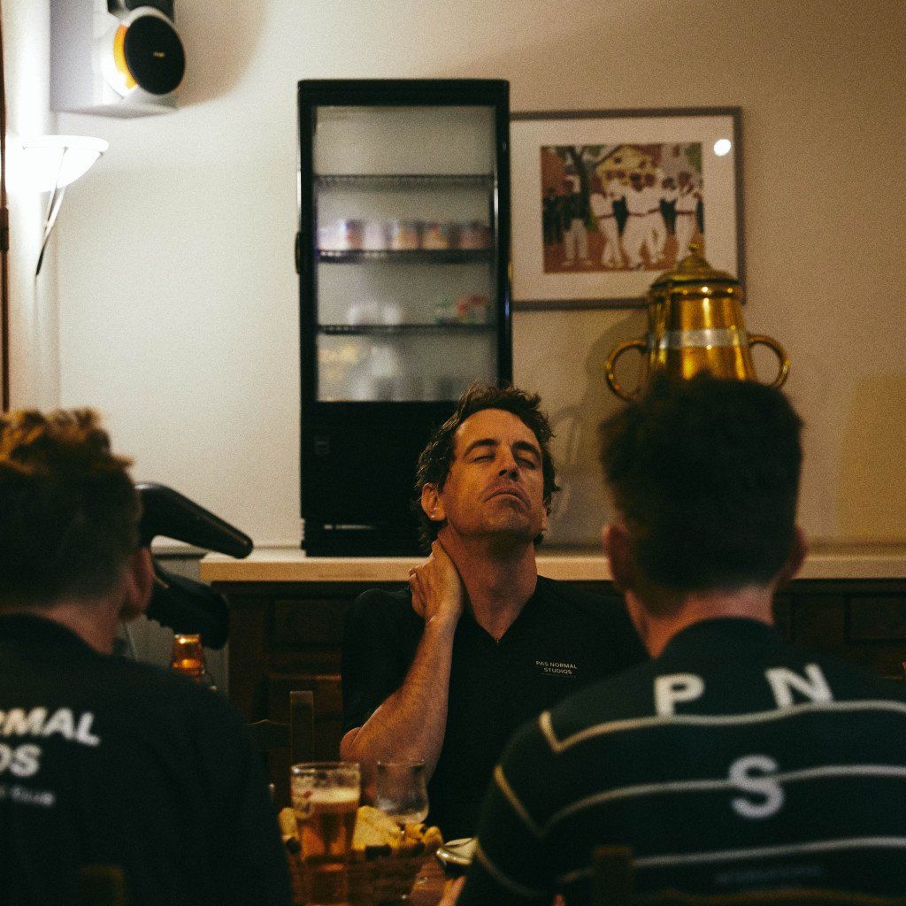 Model wearing dark t-shirt with chest branding in casual restaurant setting