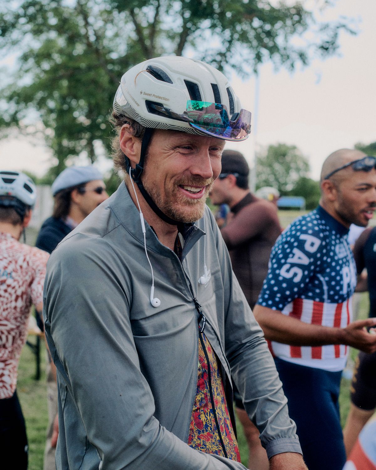 Model wearing grey long-sleeve jersey with white cycling helmet at outdoor cycling event