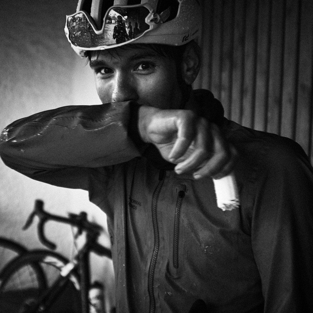 Model wearing cycling helmet adjusting dark hoodie in black and white portrait