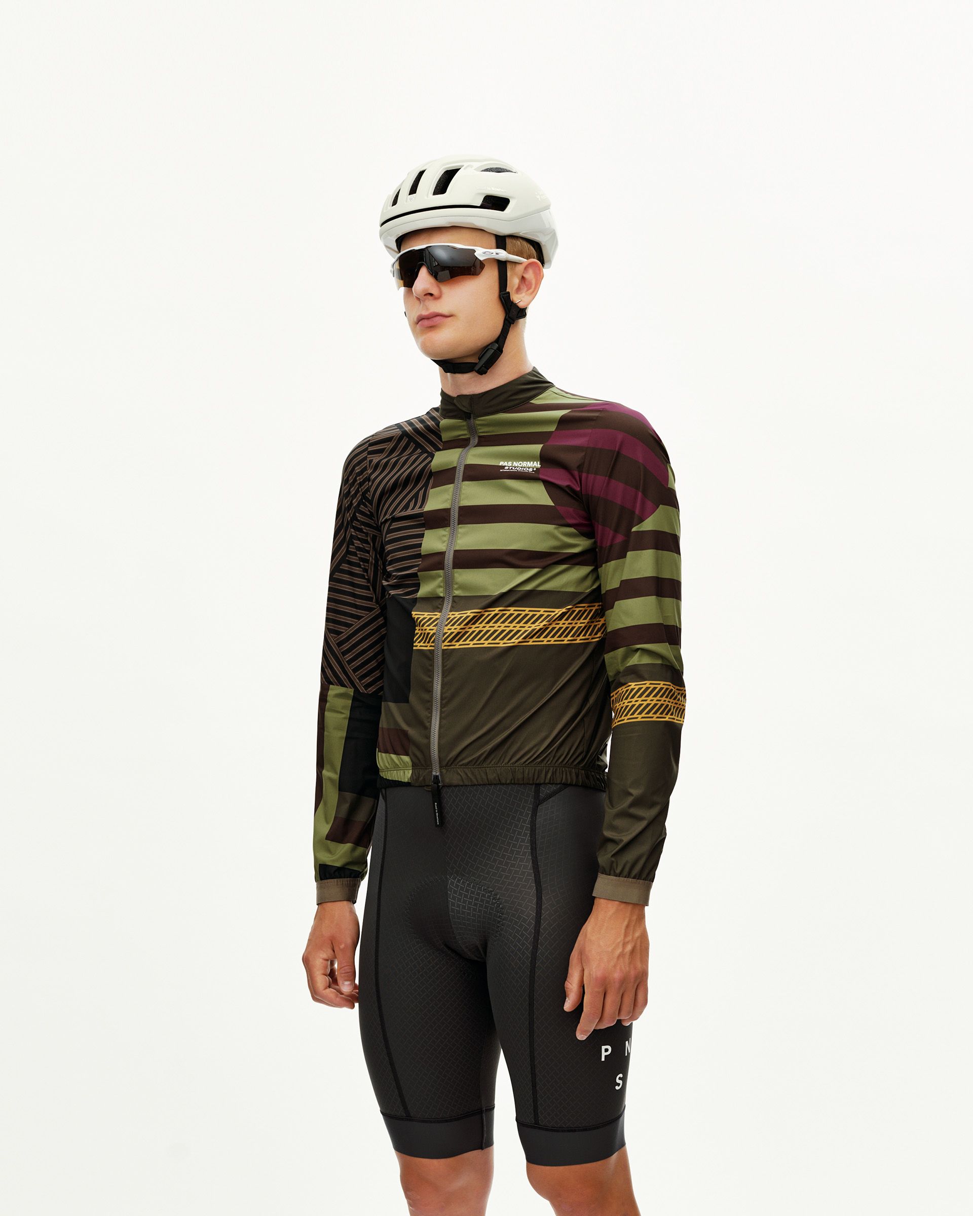 International Green Mechanism Stow Away cycling jacket on model, three-quarter front view with multicolor stripe and chest