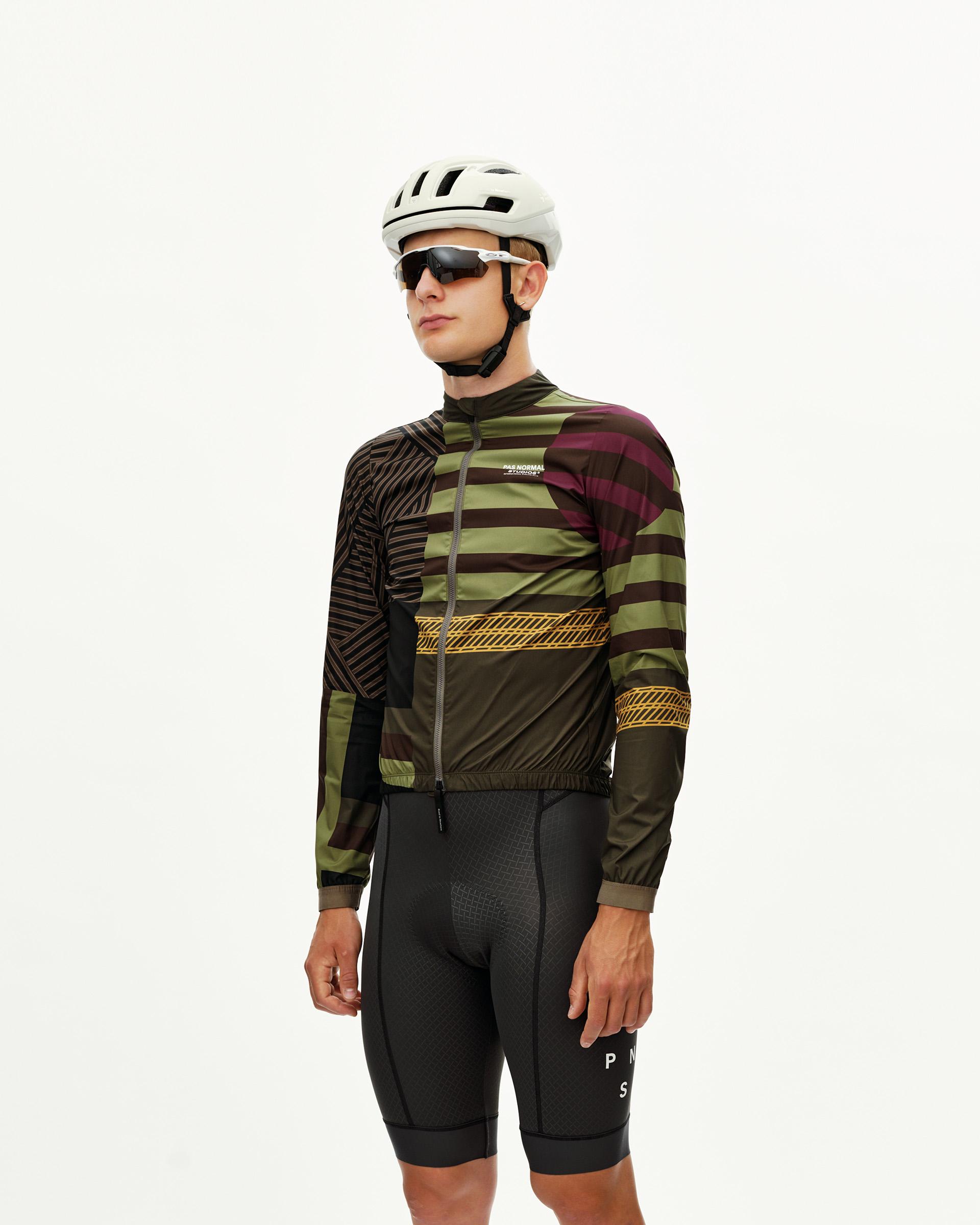 International Green Mechanism Stow Away cycling jacket on model, three-quarter front view with multicolor stripe and chest