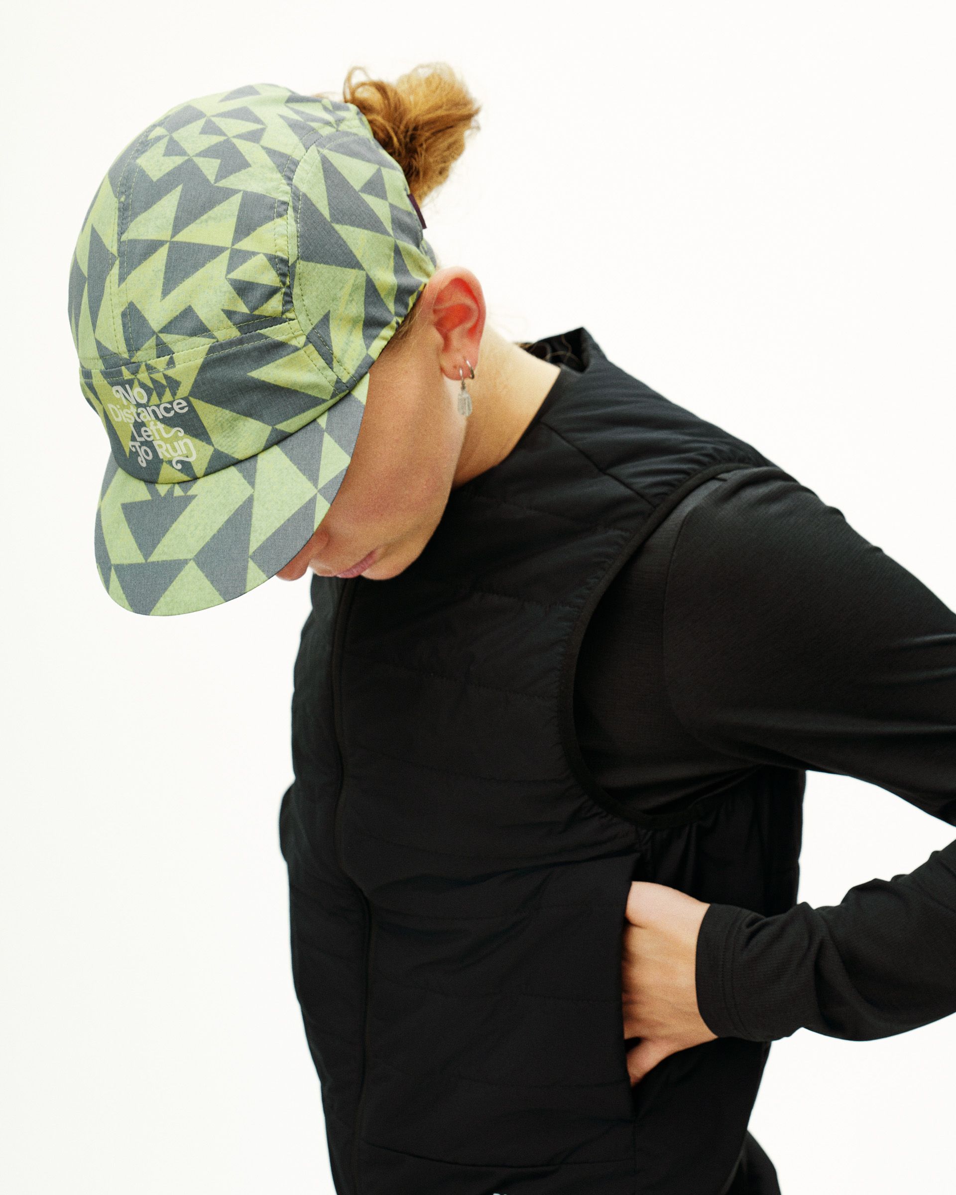 Green Origami Balance cycling cap on model, side view with geometric triangle print and text logo on brim