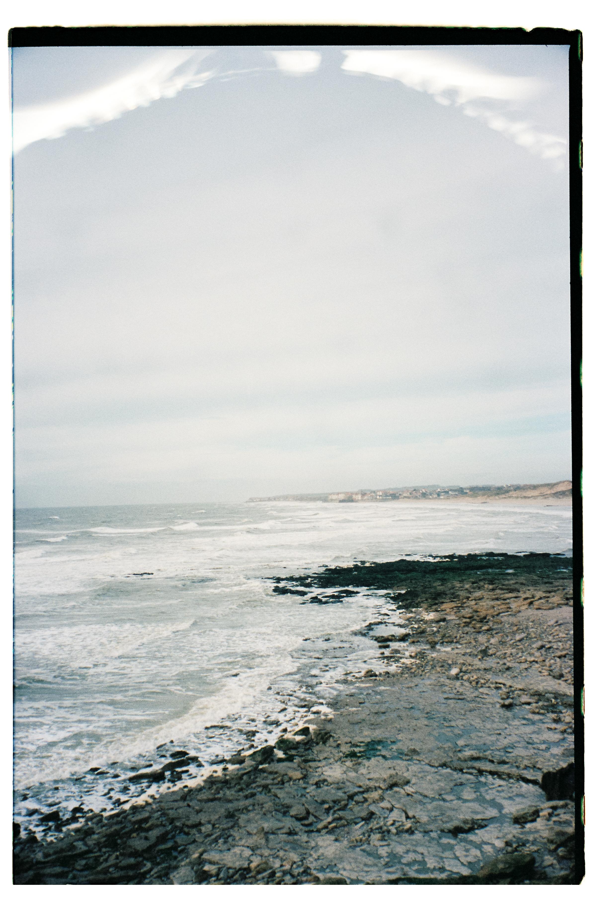 Rocky coastline with waves breaking on shore under cloudy sky