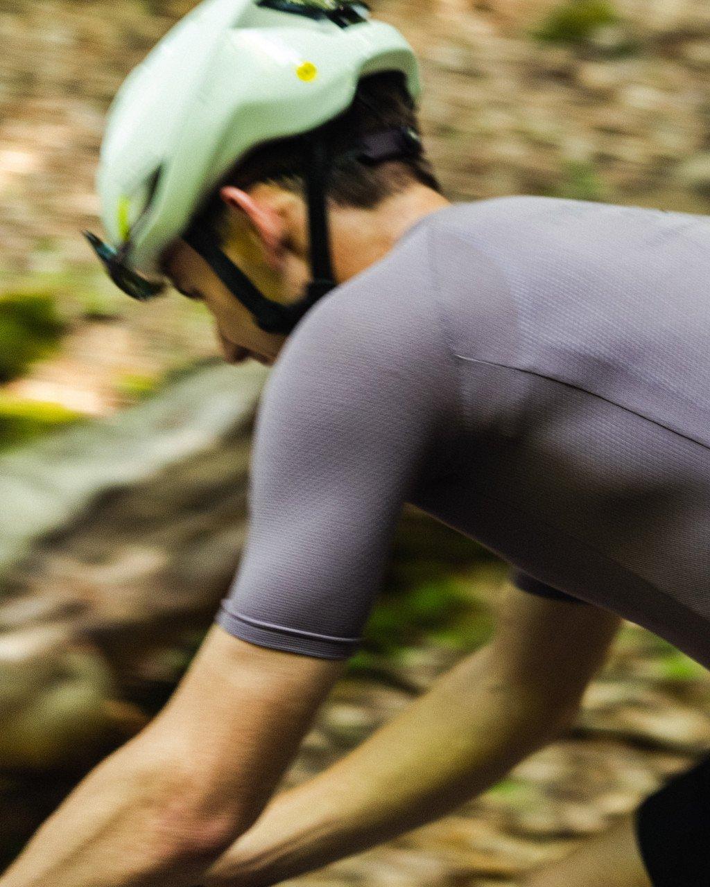 Model wearing grey cycling shorts with green helmet in riding position outdoors