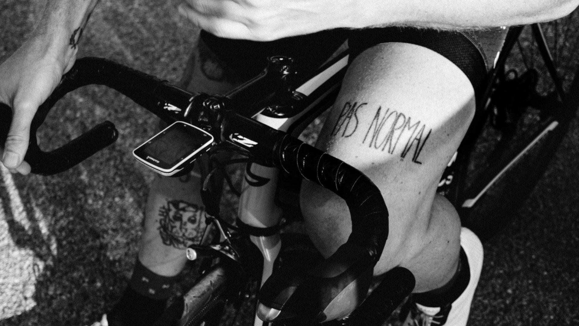 Cyclist in aerodynamic position on time trial bike with logo branding on back, black and white photograph