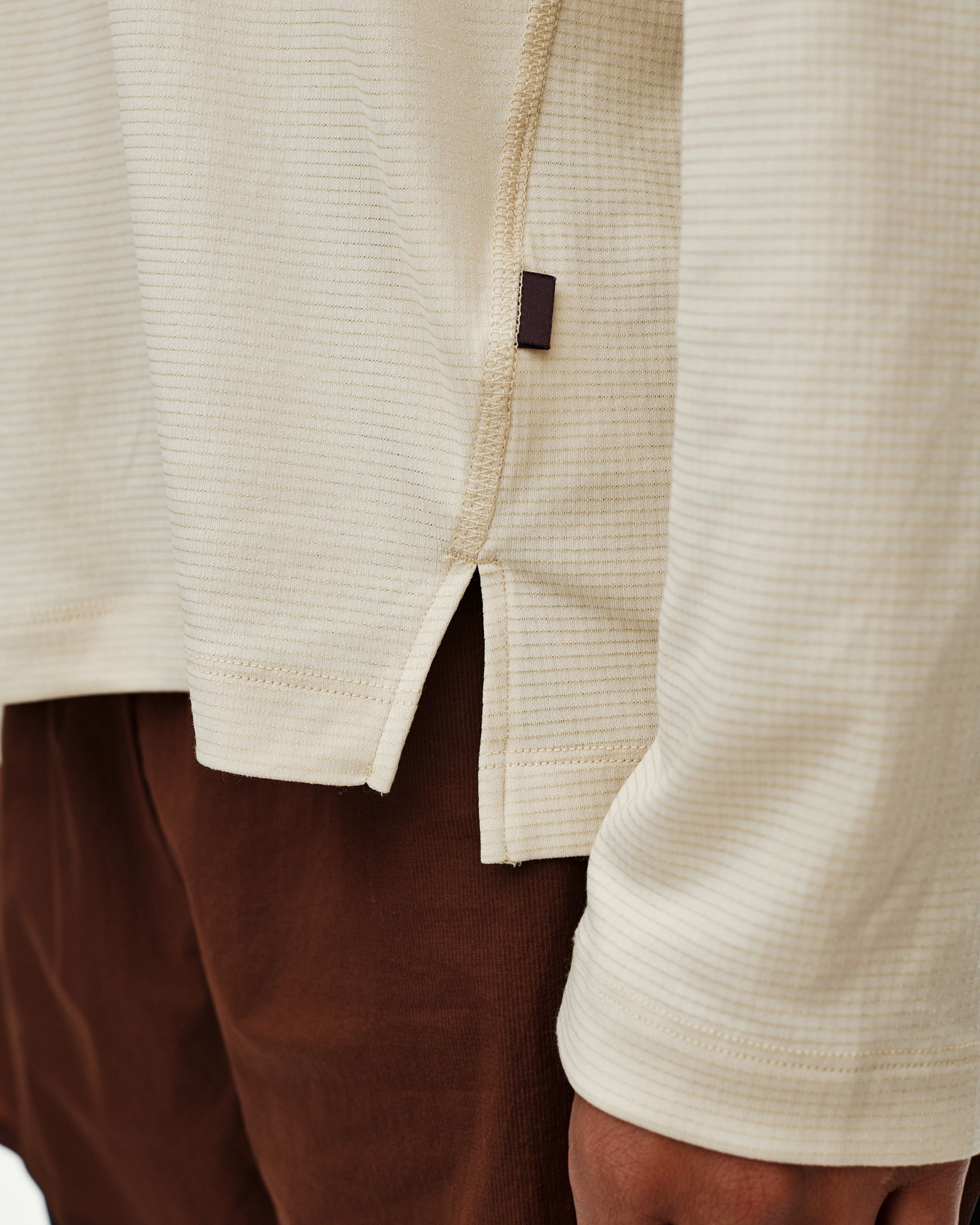 Sand Balance long sleeve T-shirt, side detail on model with hem vent and woven label