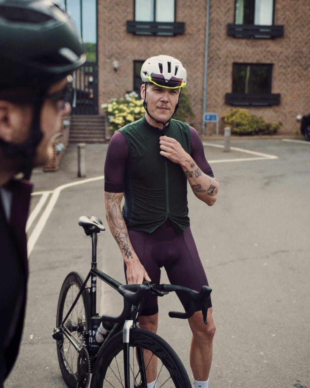 Model wearing green cycling vest and burgundy shorts with time trial bike on urban street