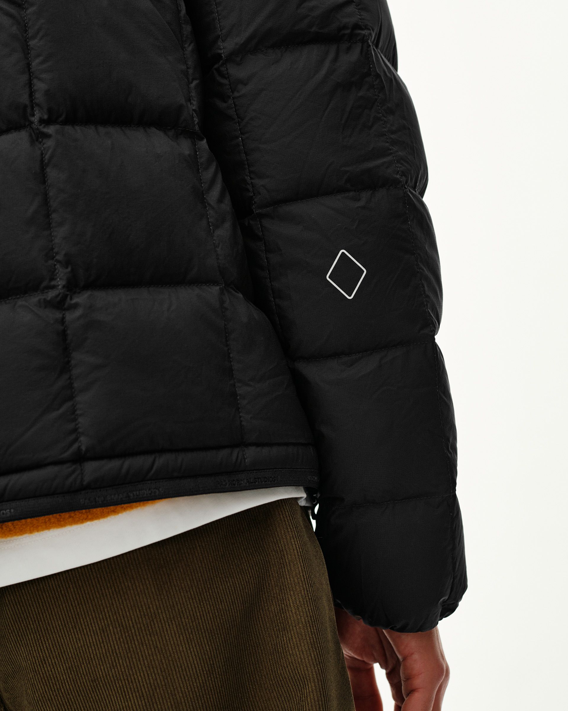 Black Off-Race Down Liner jacket, side detail view on model with white diamond logo on sleeve