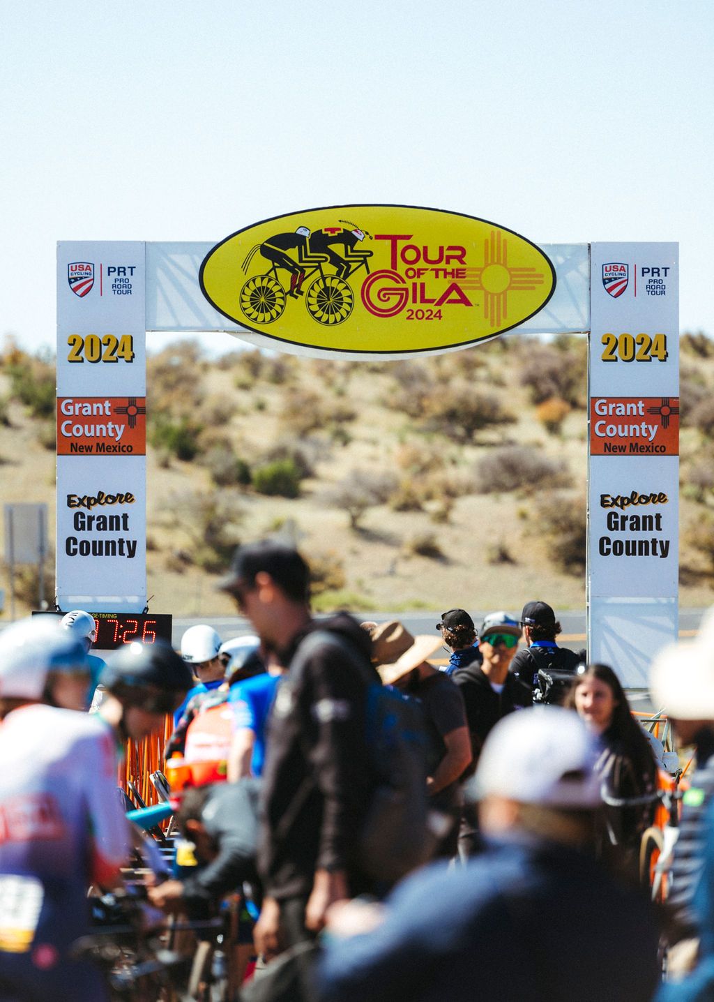 Tour of Gila race finish line with crowds and yellow event banner in desert landscape