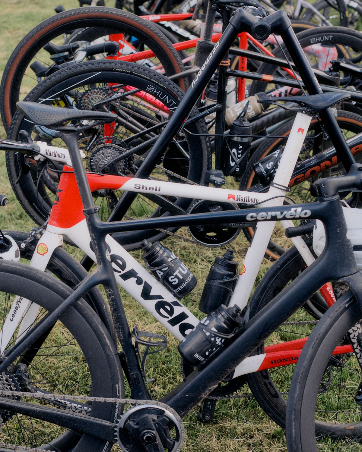 Professional cycling bikes stacked together after race, featuring team sponsors and branding on frames