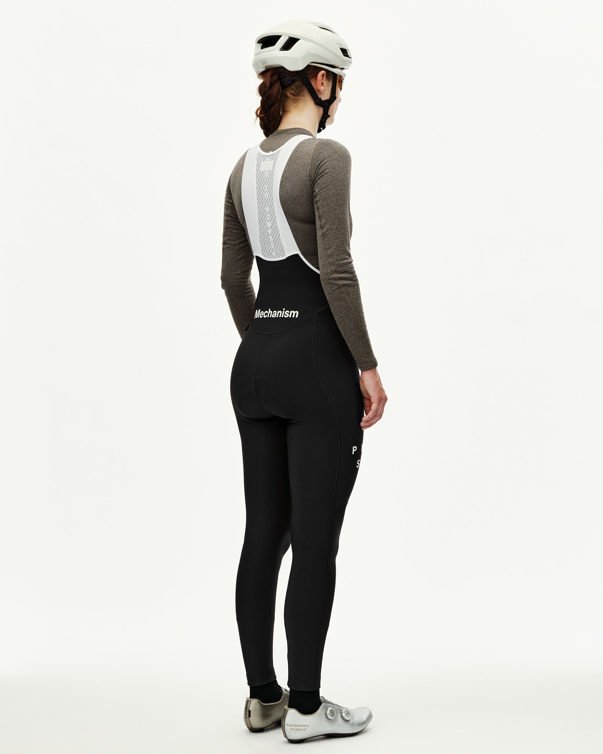 Black Mechanism women's cycling thermal long bibs on model, rear view with white mesh bib straps