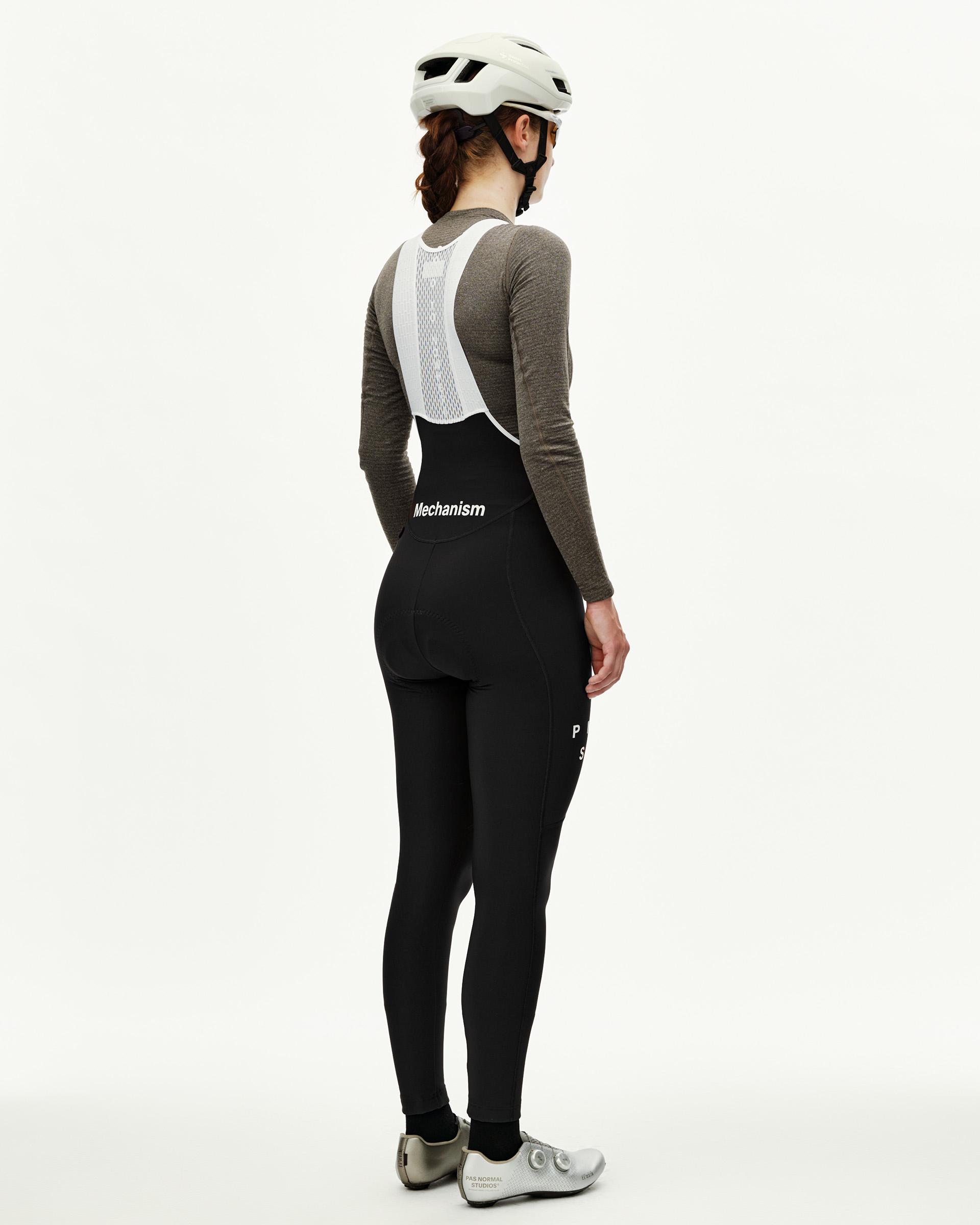 Black Mechanism women's cycling thermal long bibs on model, rear view with white mesh bib straps