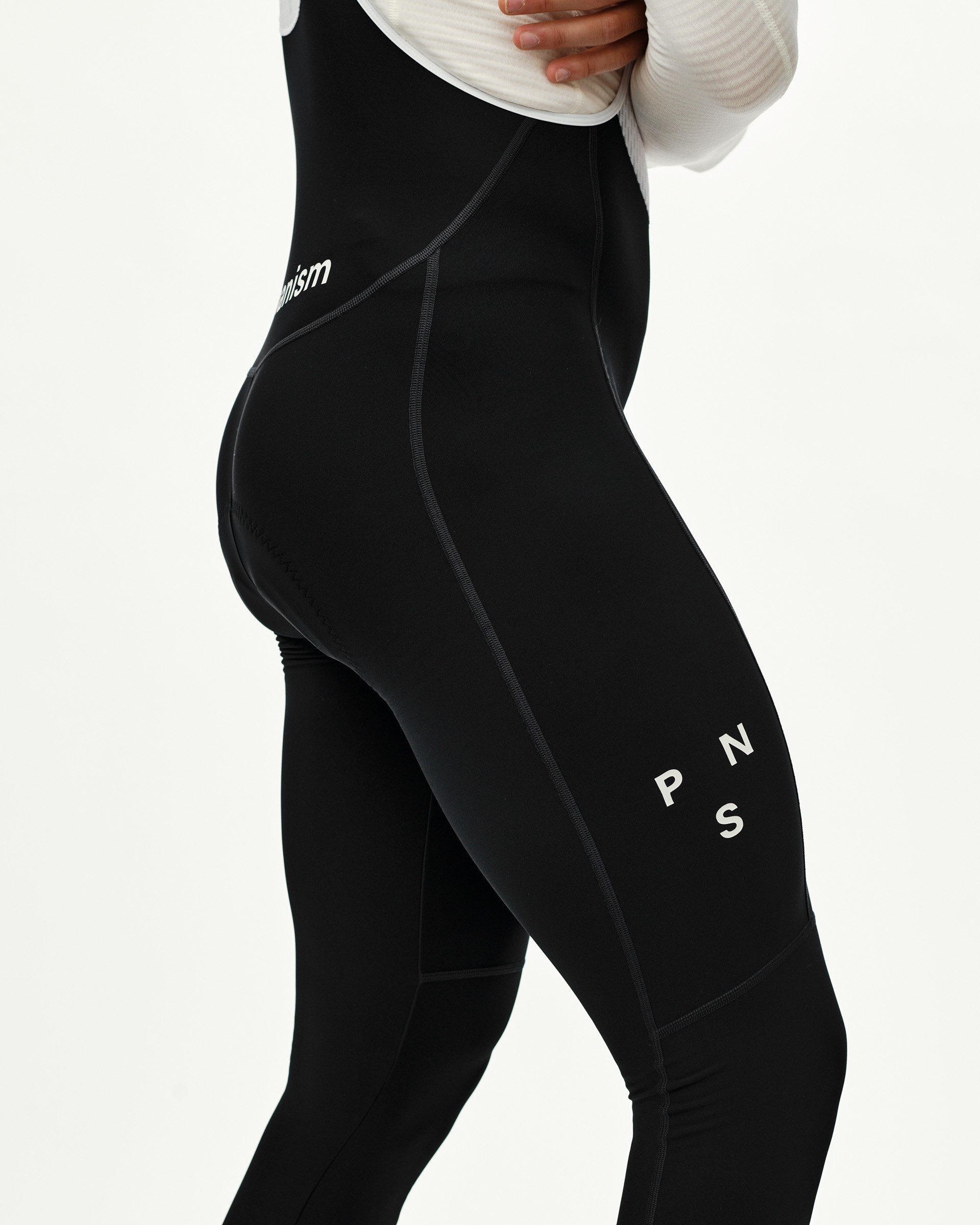Black Mechanism cycling bib tights on model, three-quarter rear view with white leg logo