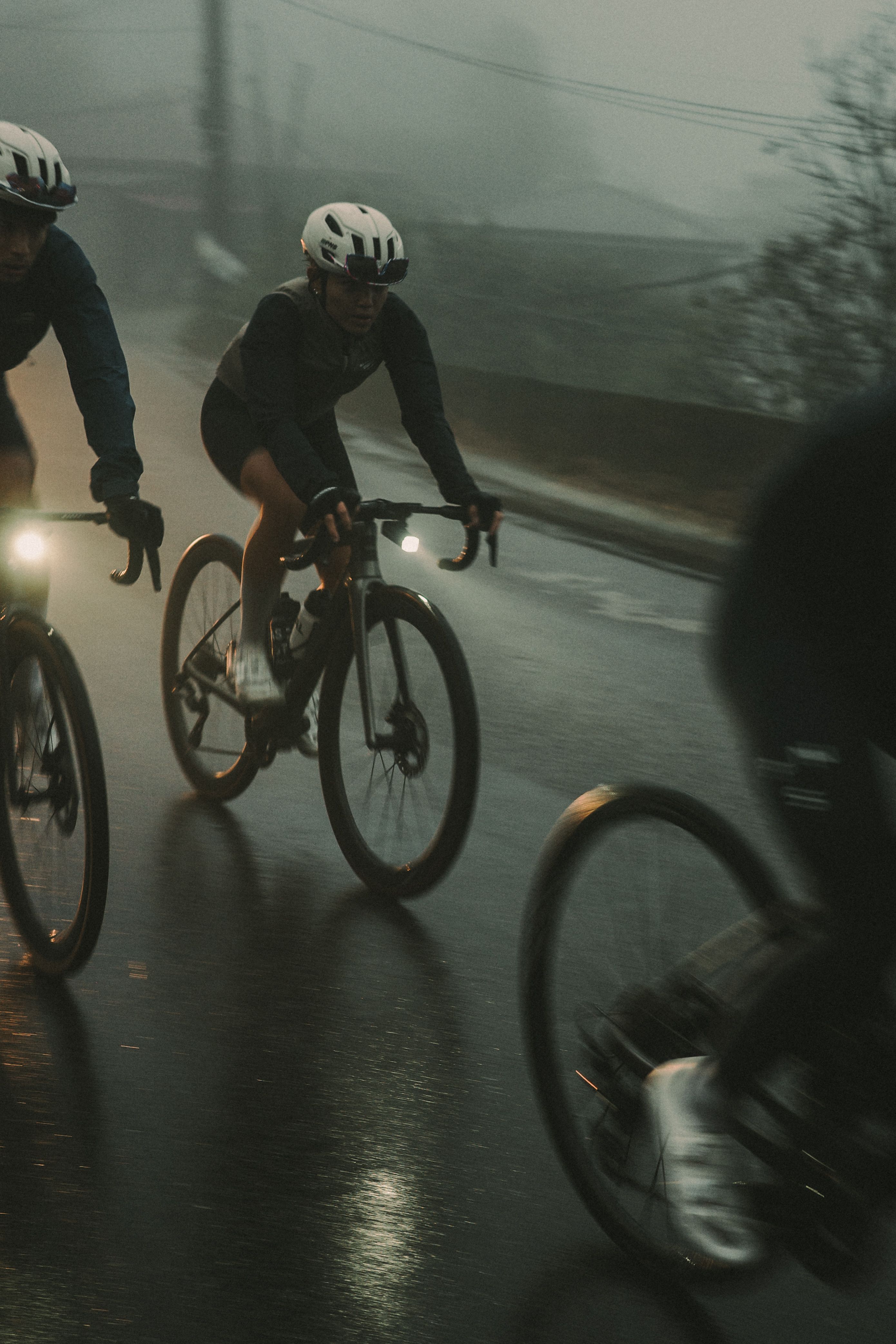 Cyclists riding in dark conditions on wet road with bike lights