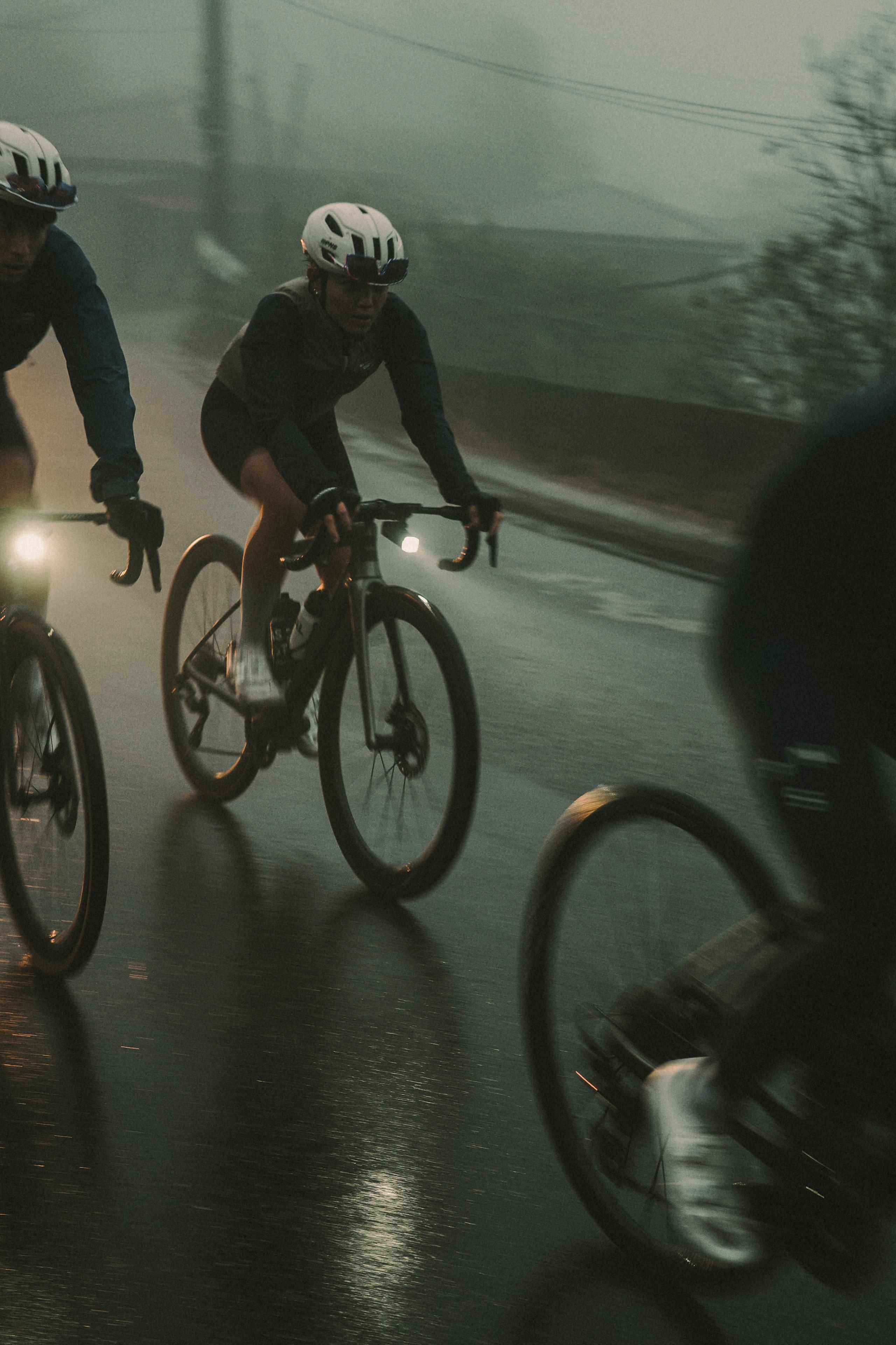 Cyclists riding in dark conditions on wet road with bike lights