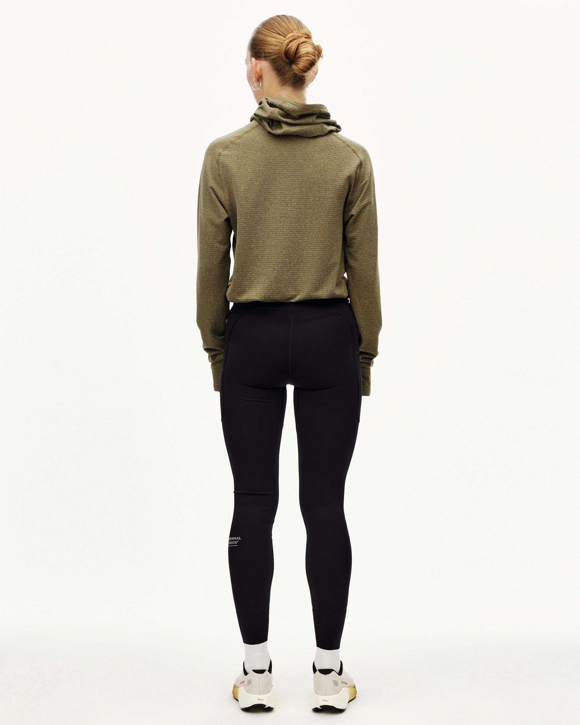 Black Balance long tights on model, rear view with fitted silhouette and logo print at lower leg