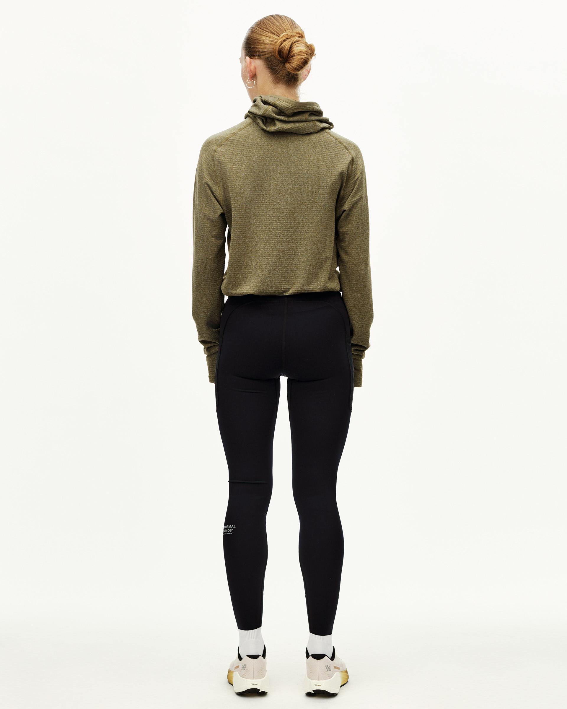 Black Balance long tights on model, rear view with fitted silhouette and logo print at lower leg