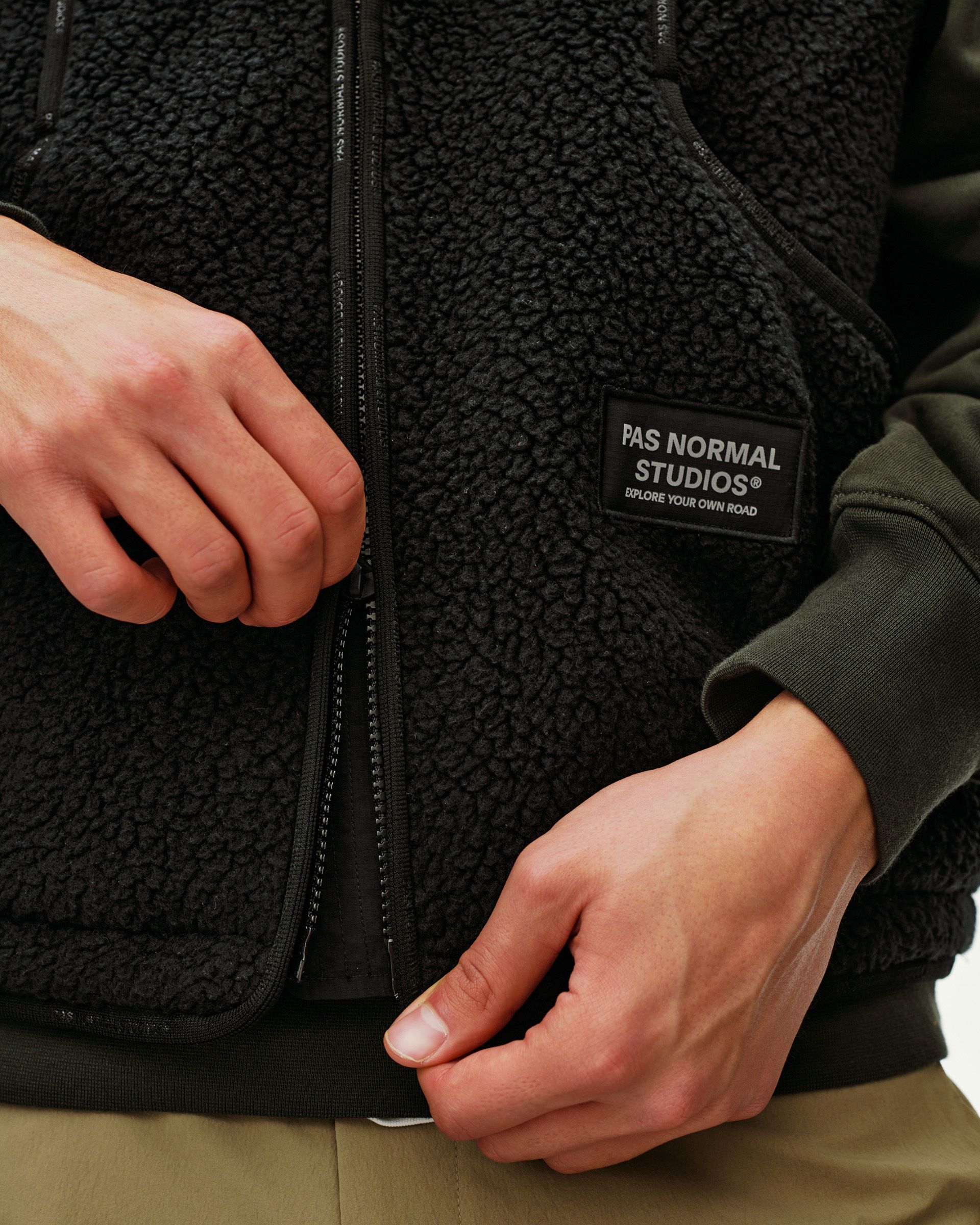 Black Off-Race Pile Fleece vest, detail view on model showing front zip and woven chest patch