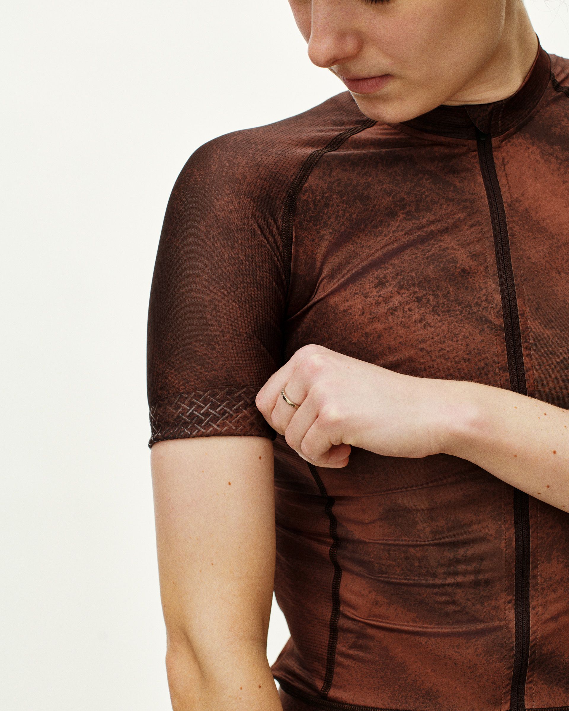 Brown Mechanism cycling jersey on model with textured sleeve cuffs and dotted body pattern