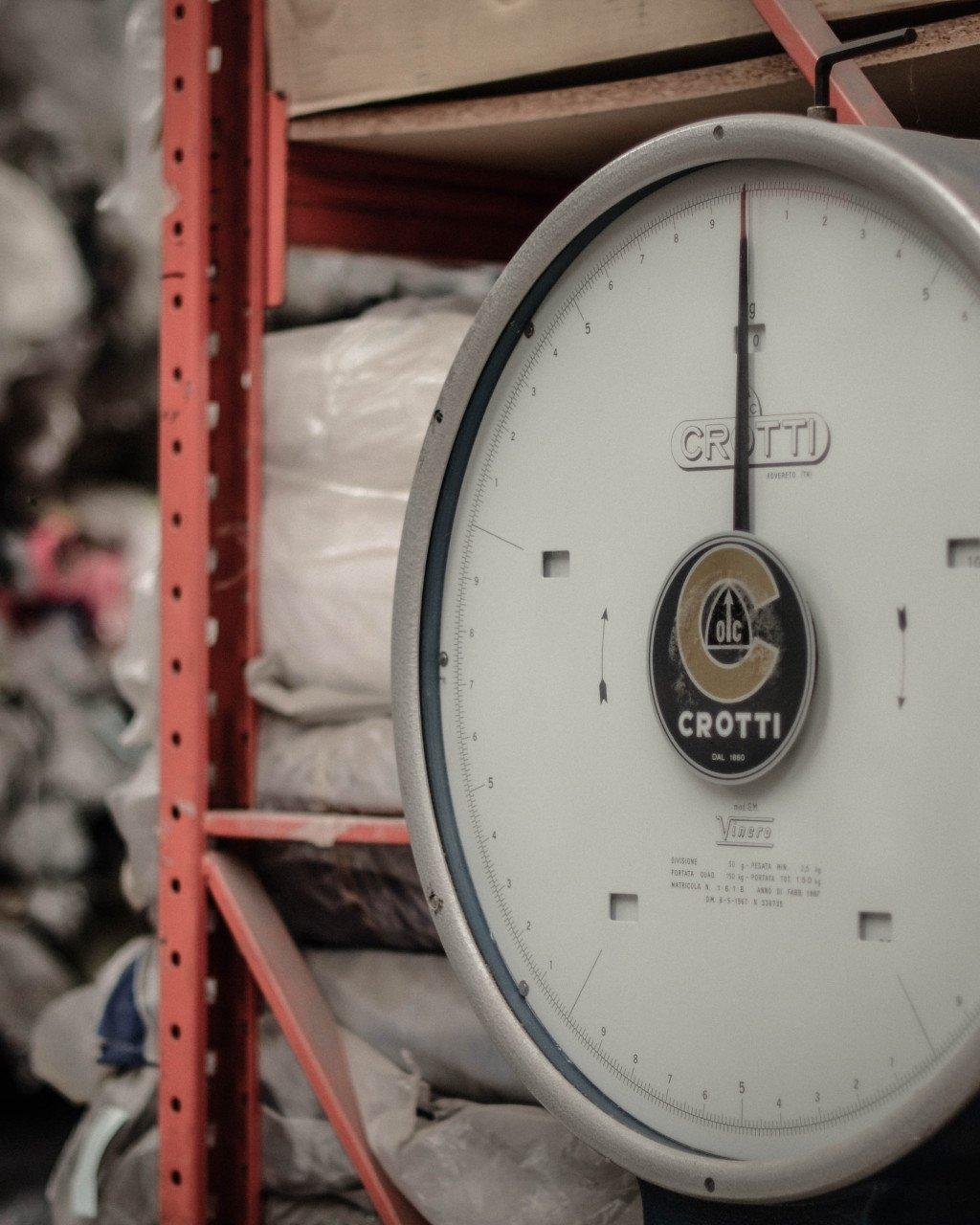 Vintage Crotti scale in warehouse setting with fabric rolls on shelving
