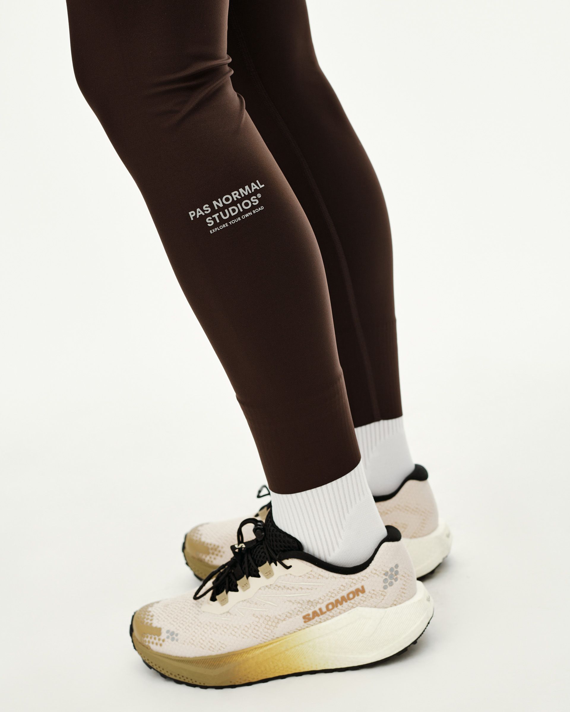 Dark Coffee brown Balance women's long tights, side detail on model with white logo print at calf